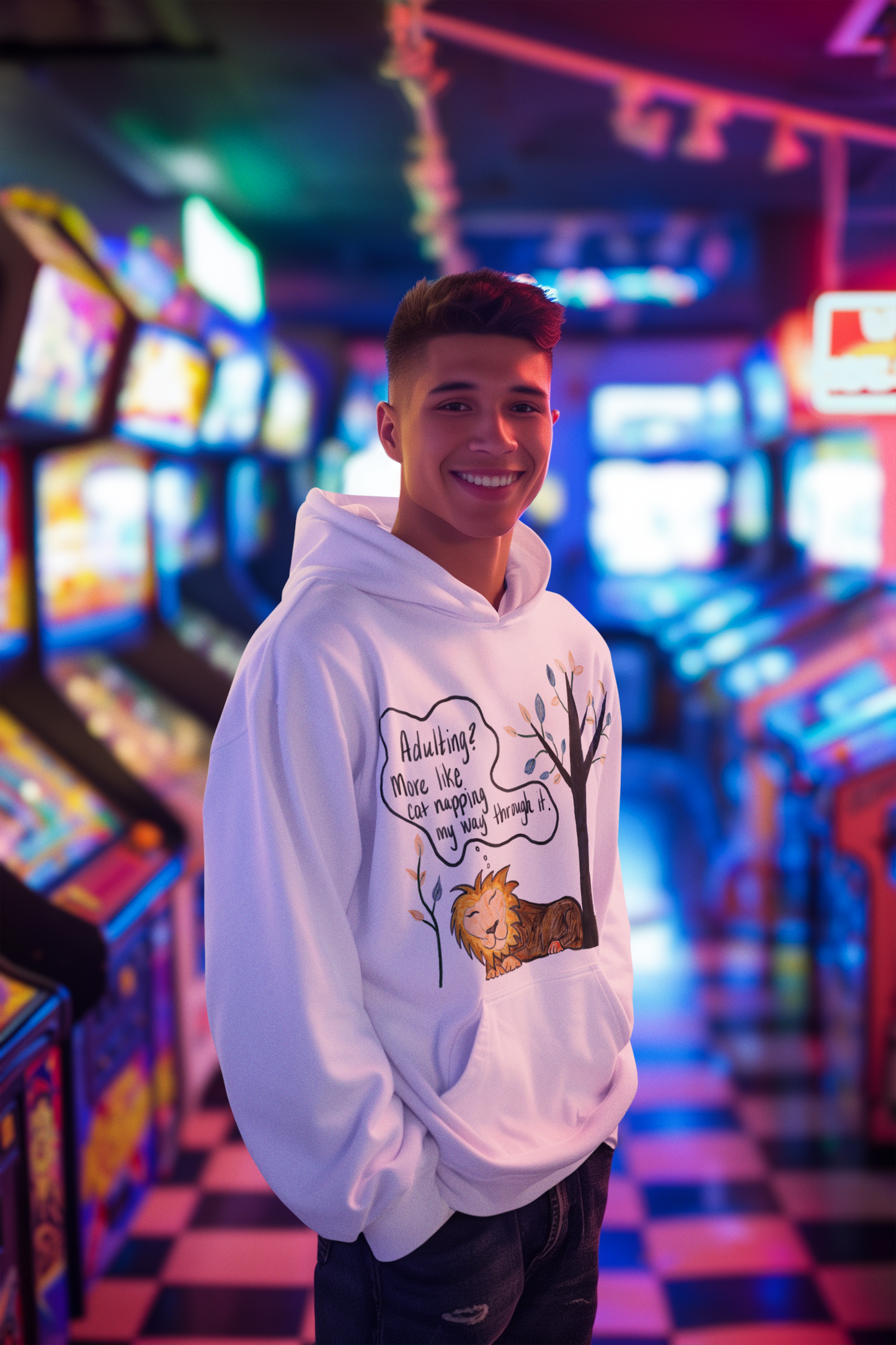 Young man wearing white Adulting Nap Lion hoodie smiling in arcade – sarcastic affirmation lazy vibes hoodie by GrungePup Sarcastic Affirmations