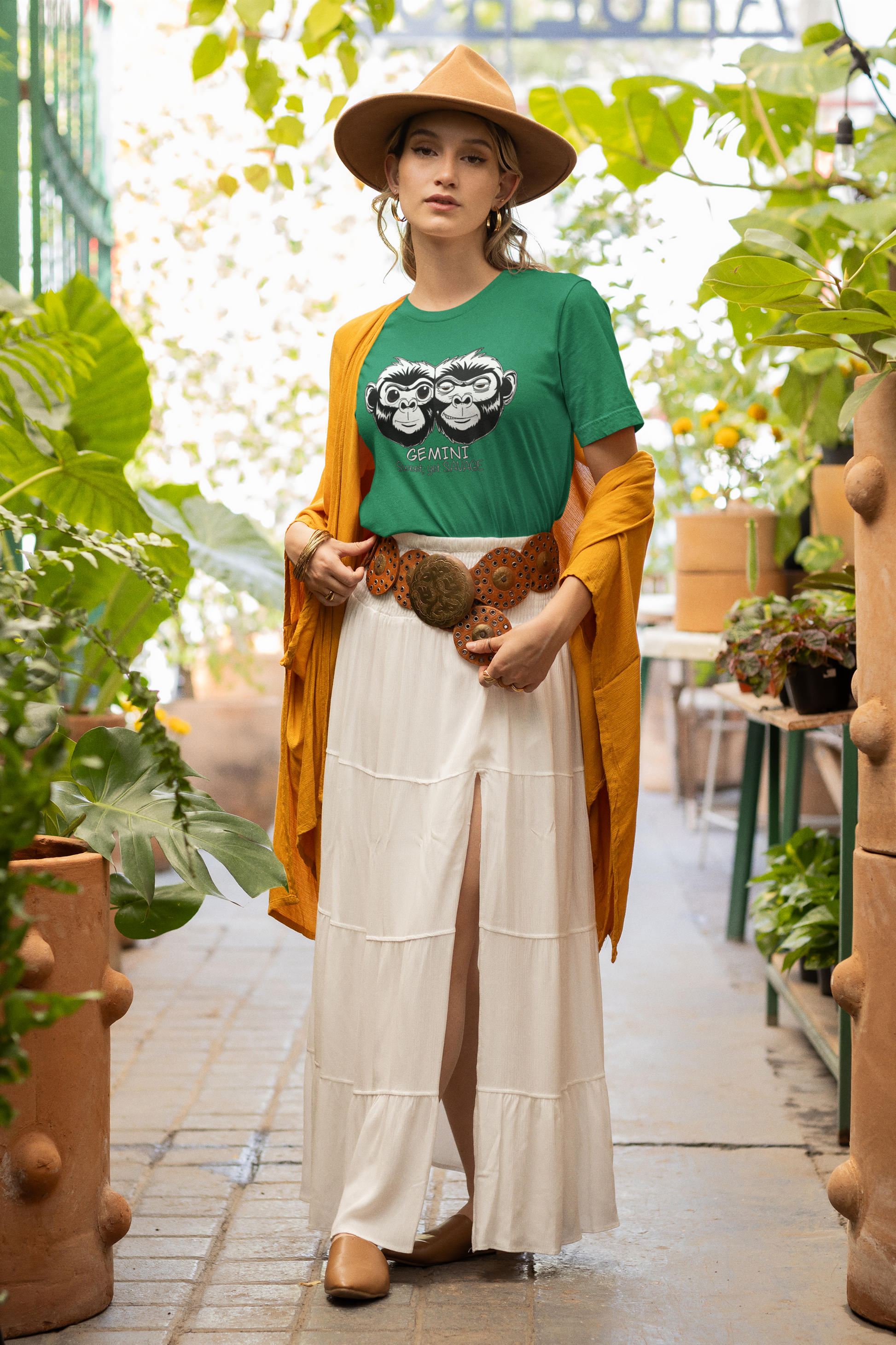 Woman in boho outfit wearing a kelly green Gemini t-shirt while standing among plants