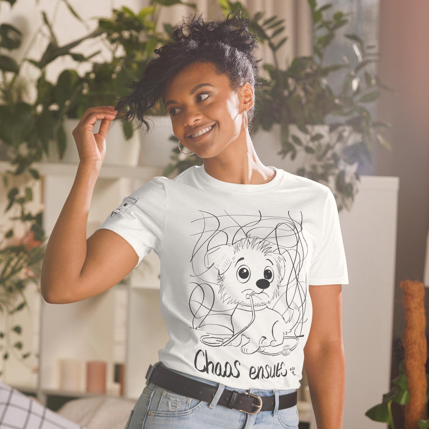 Woman wearing white Chaos Ensues t-shirt with chaotic vet dog illustration in plant-filled room – GrungePup Vet Chaos humor apparel