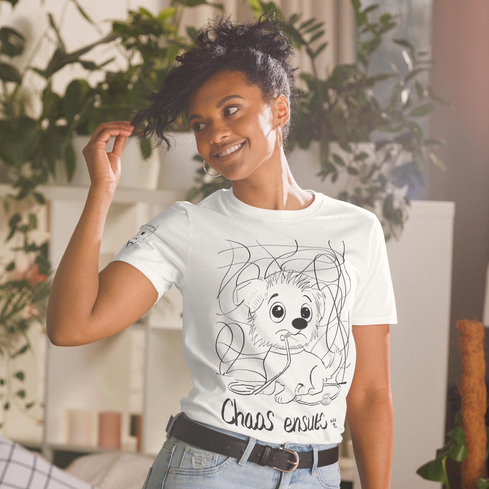 Woman wearing white Chaos Ensues t-shirt with chaotic vet dog illustration in plant-filled room – GrungePup Vet Chaos humor apparel