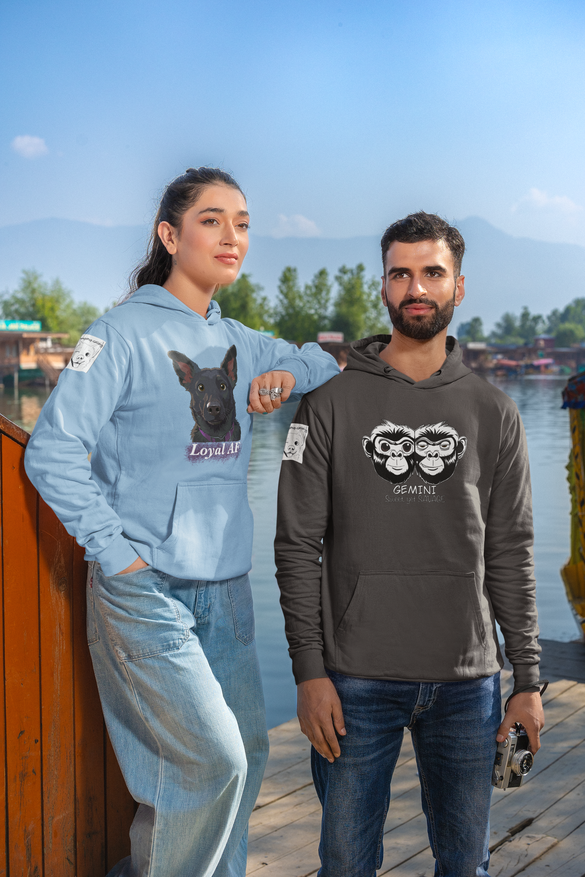 Couple standing by the lake, woman wearing light blue Mathis Loyal AF hoodie and man wearing Gemini hoodie