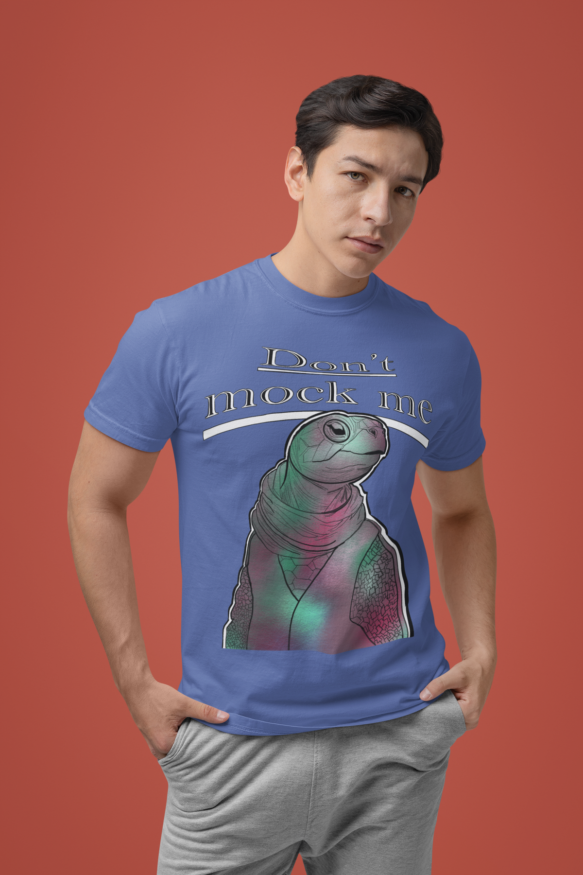 Young man posing with a serious look against a red background wearing a mystic blue Comfort Colors 1717 t-shirt with the Don’t Mock Me design
