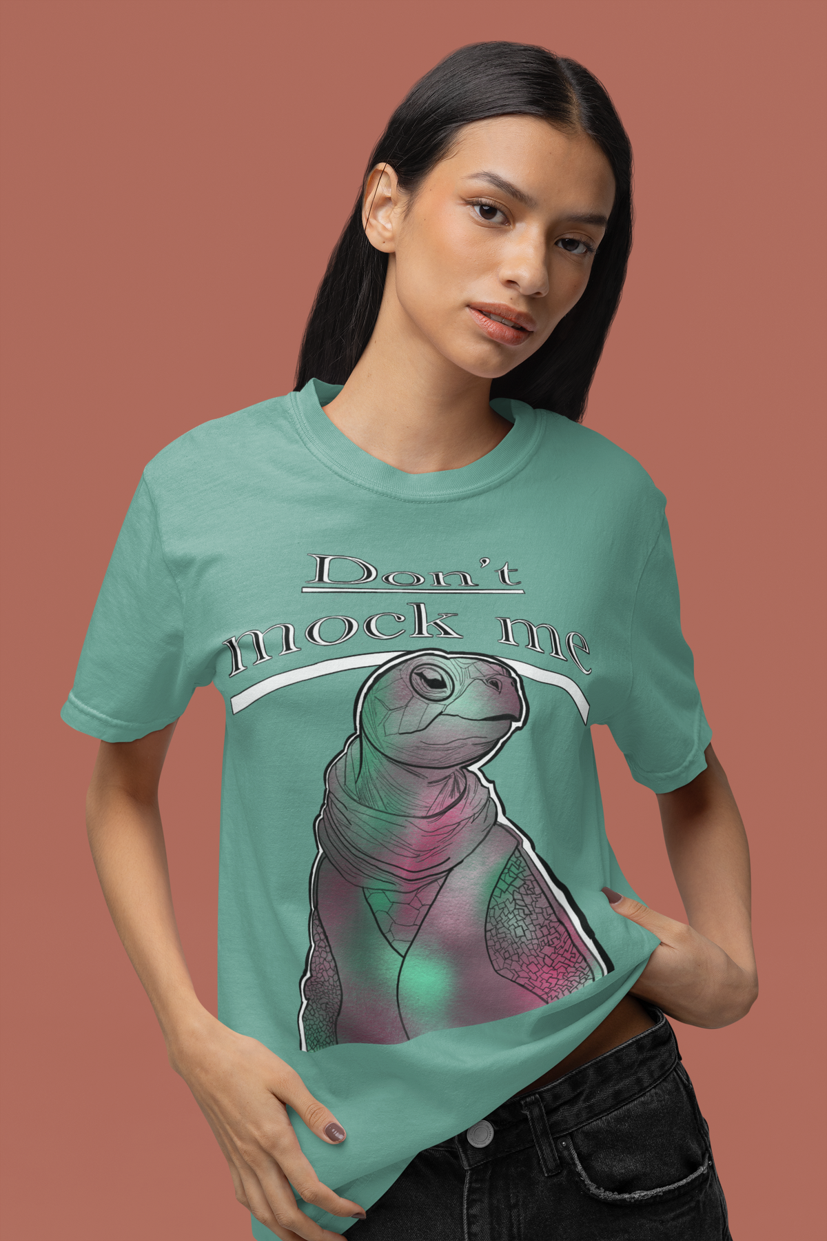 Woman standing against a pink background wearing a seafoam Comfort Colors 1717 t-shirt with the Don’t Mock Me design