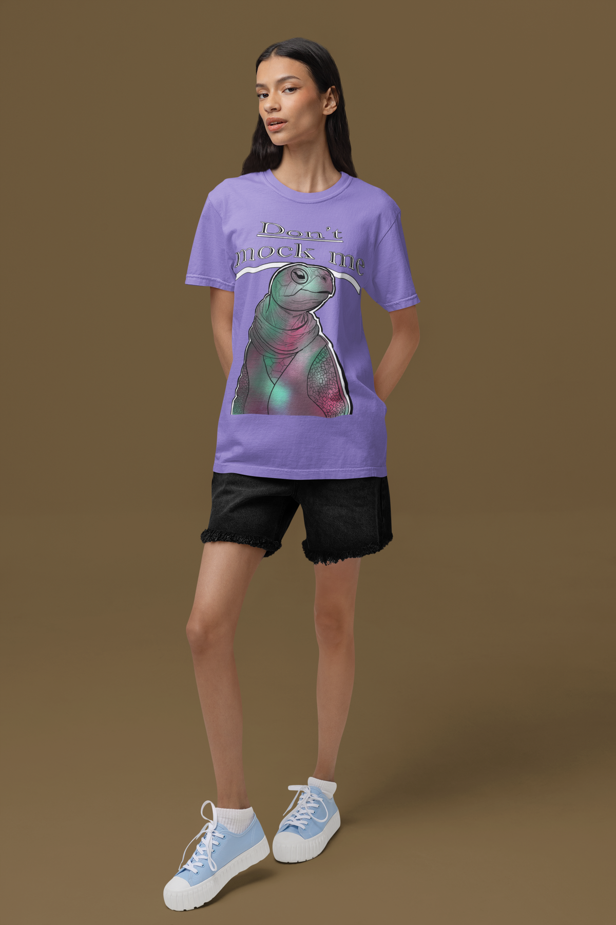 Stylish woman with long dark hair wearing a violet Comfort Colors 1717 t-shirt featuring the Don’t Mock Me design, posing against a brown background