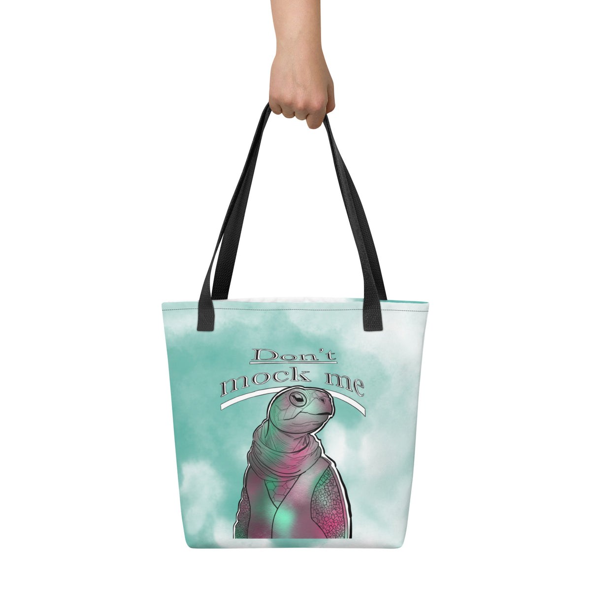 Front view of the Don’t Mock Me all-over print tote bag featuring the Mock Turtle design on a soft teal watercolor background, held by a hand