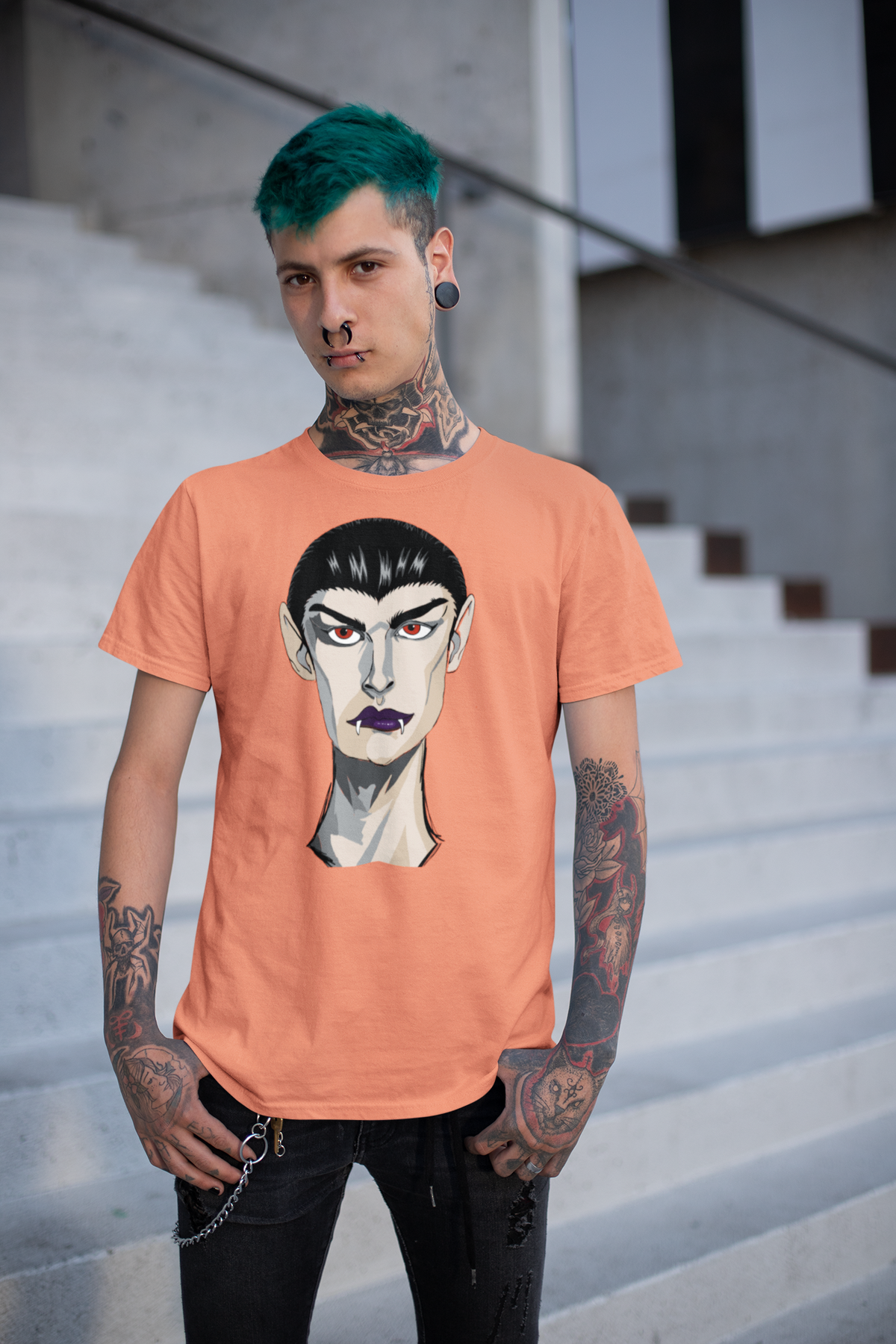 Tattooed man with green hair standing on concrete stairs wearing a heather orange t-shirt printed with the Emo Vamp vampire face.