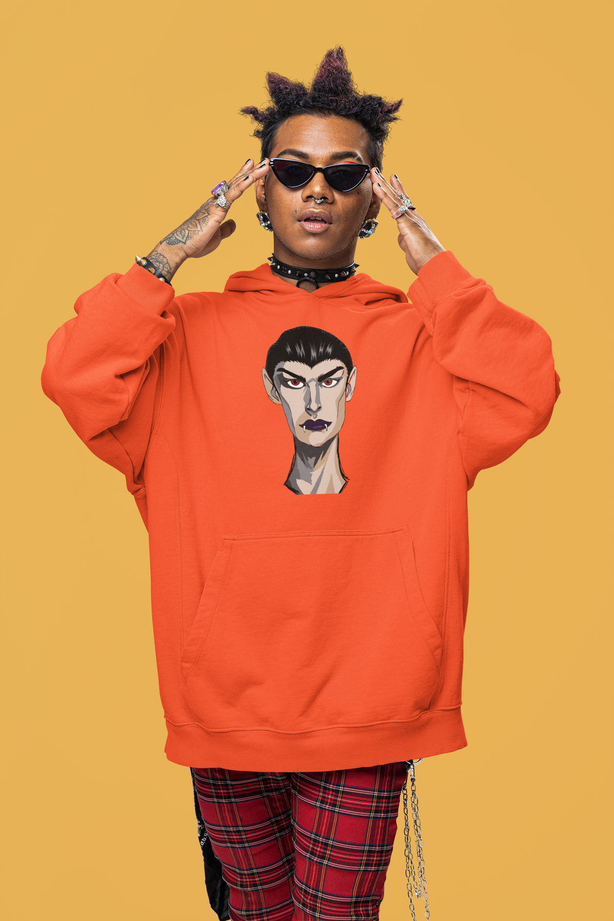 Man in black sunglasses wearing an orange hoodie printed with the Emo Vamp vampire face against a yellow background.