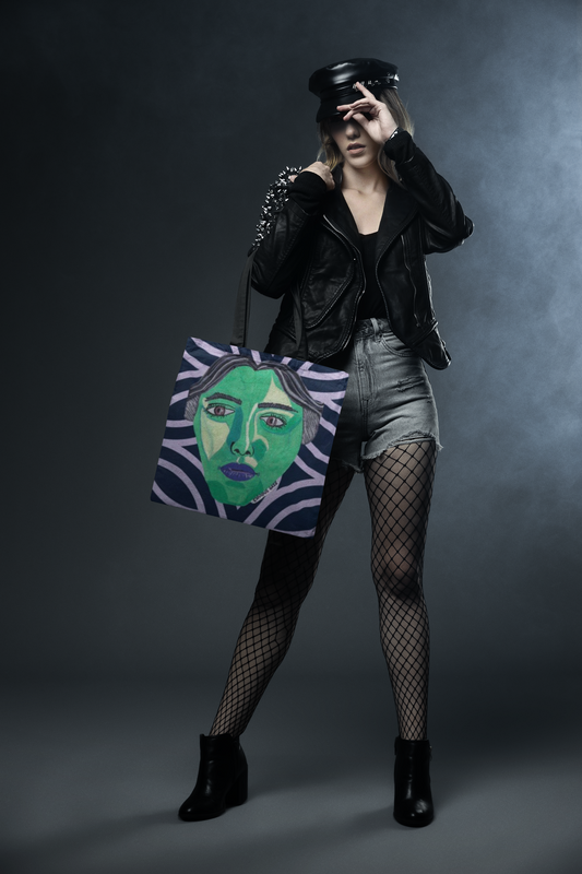 Woman standing in urban setting carrying Envious Gaze dark blue geometric tote bag with bold green face design