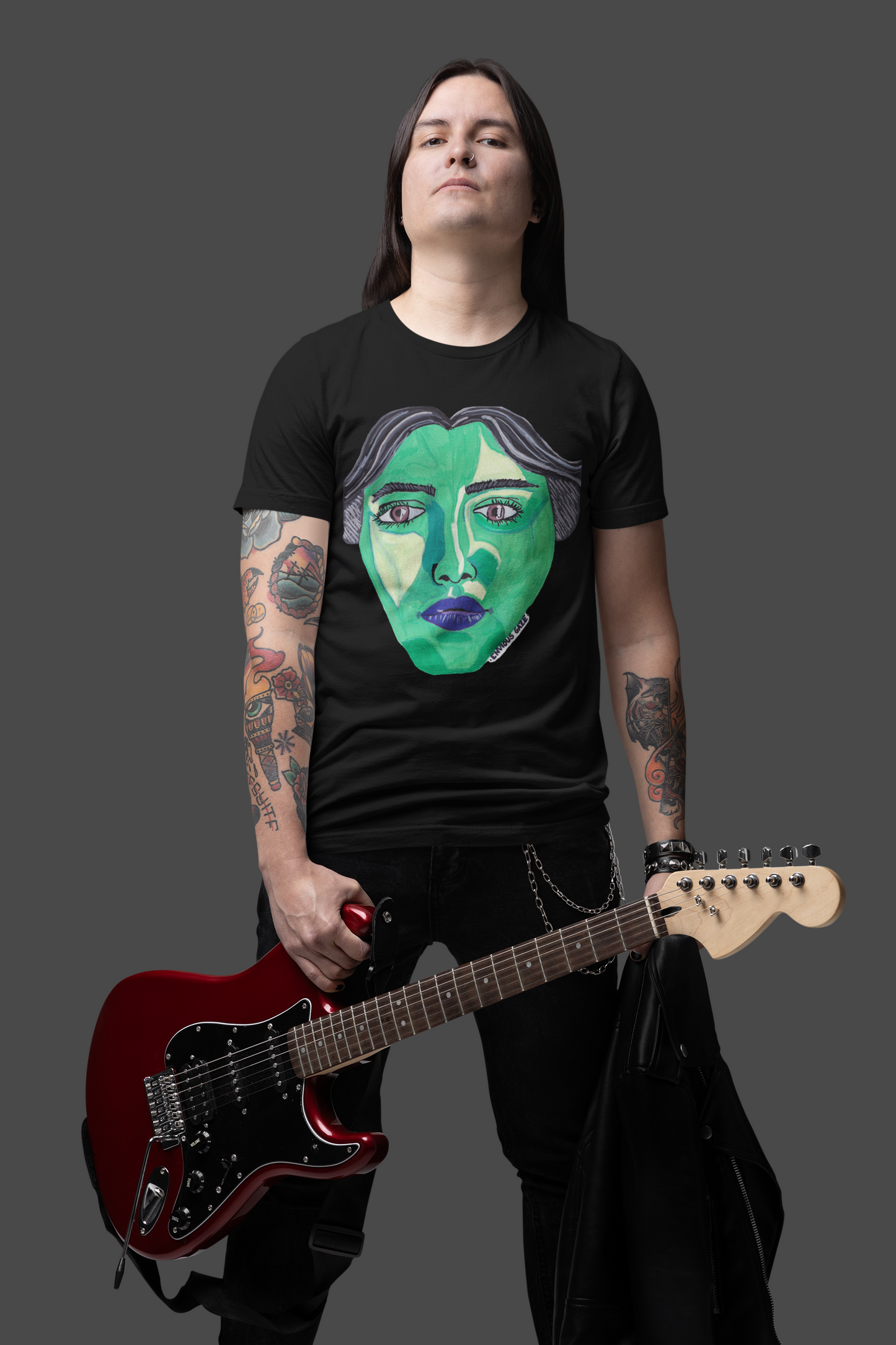 Man holding red guitar wearing black Envious Gaze t-shirt with colorful face design
