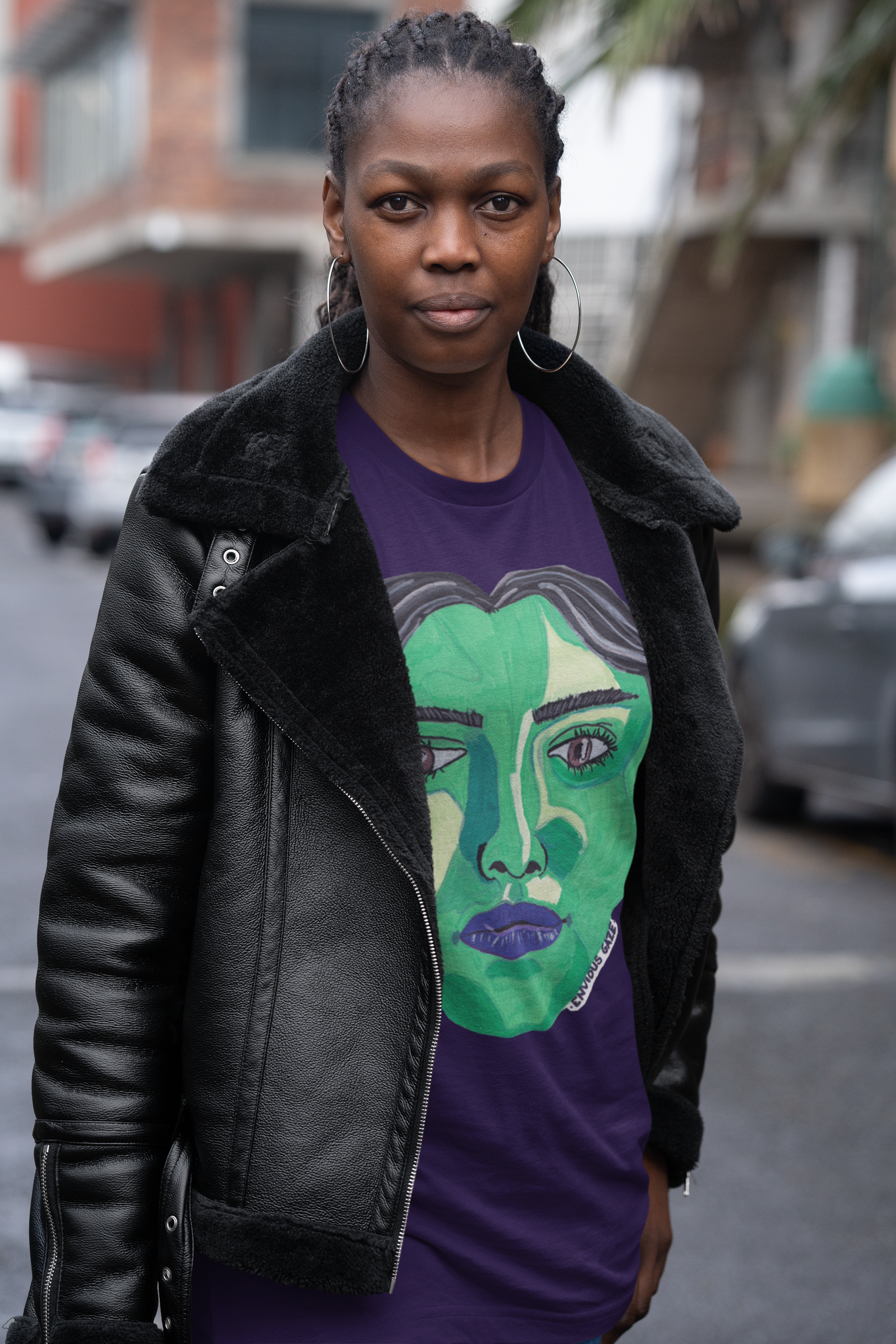 Woman wearing team purple Envious Gaze t-shirt with striking green face artwork and black jacket