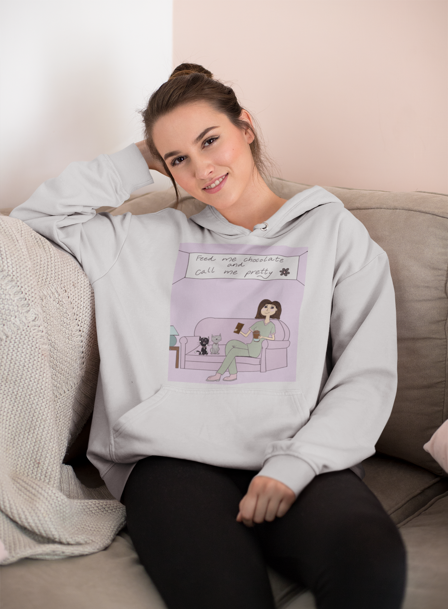 Woman sitting on couch wearing ash "Feed Me Chocolate and Call Me Pretty" hoodie – cozy sarcastic lazy vibes from GrungePup Gallery