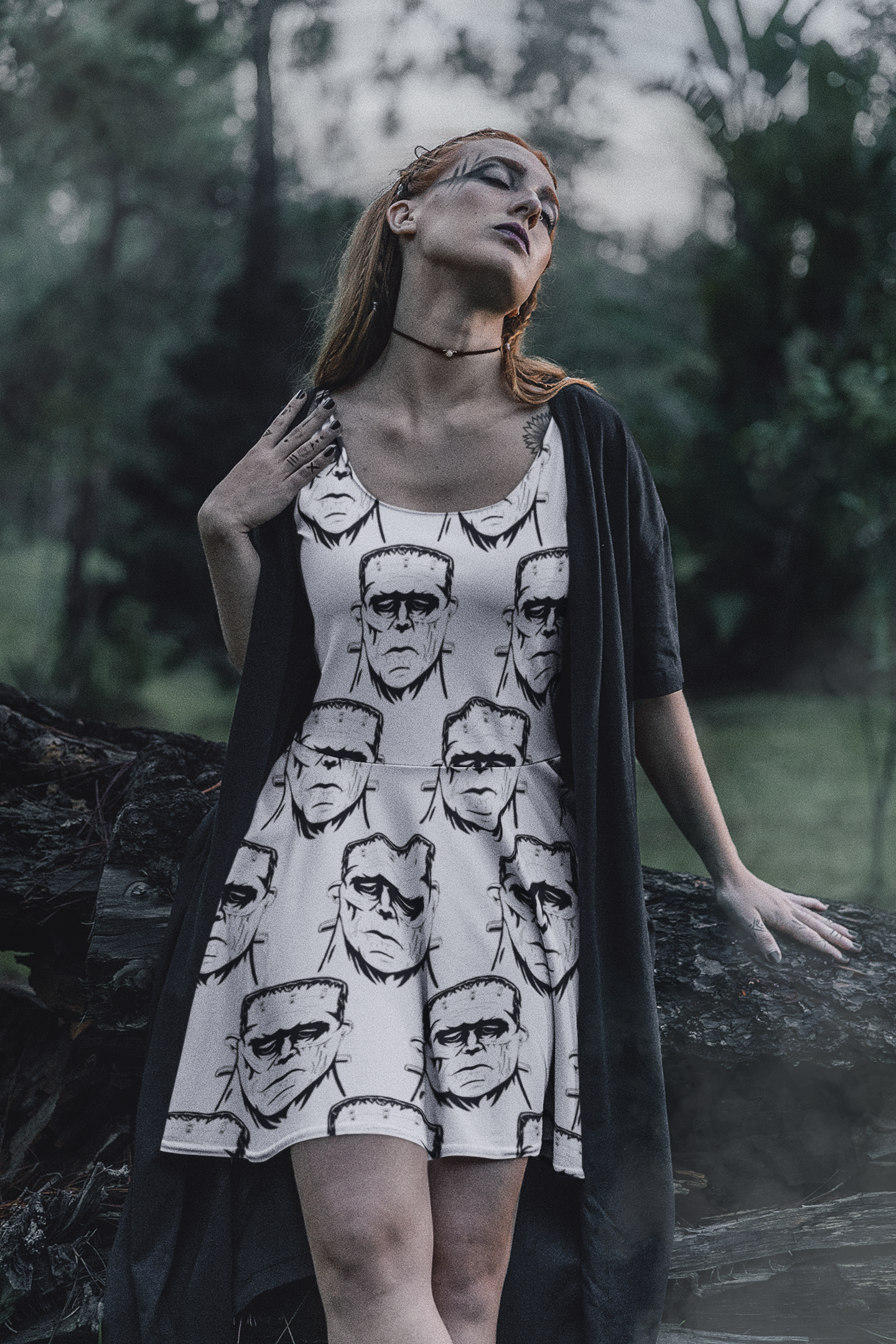 Woman with long red hair wearing Frank's Monster skater dress with black cape standing in a forest setting