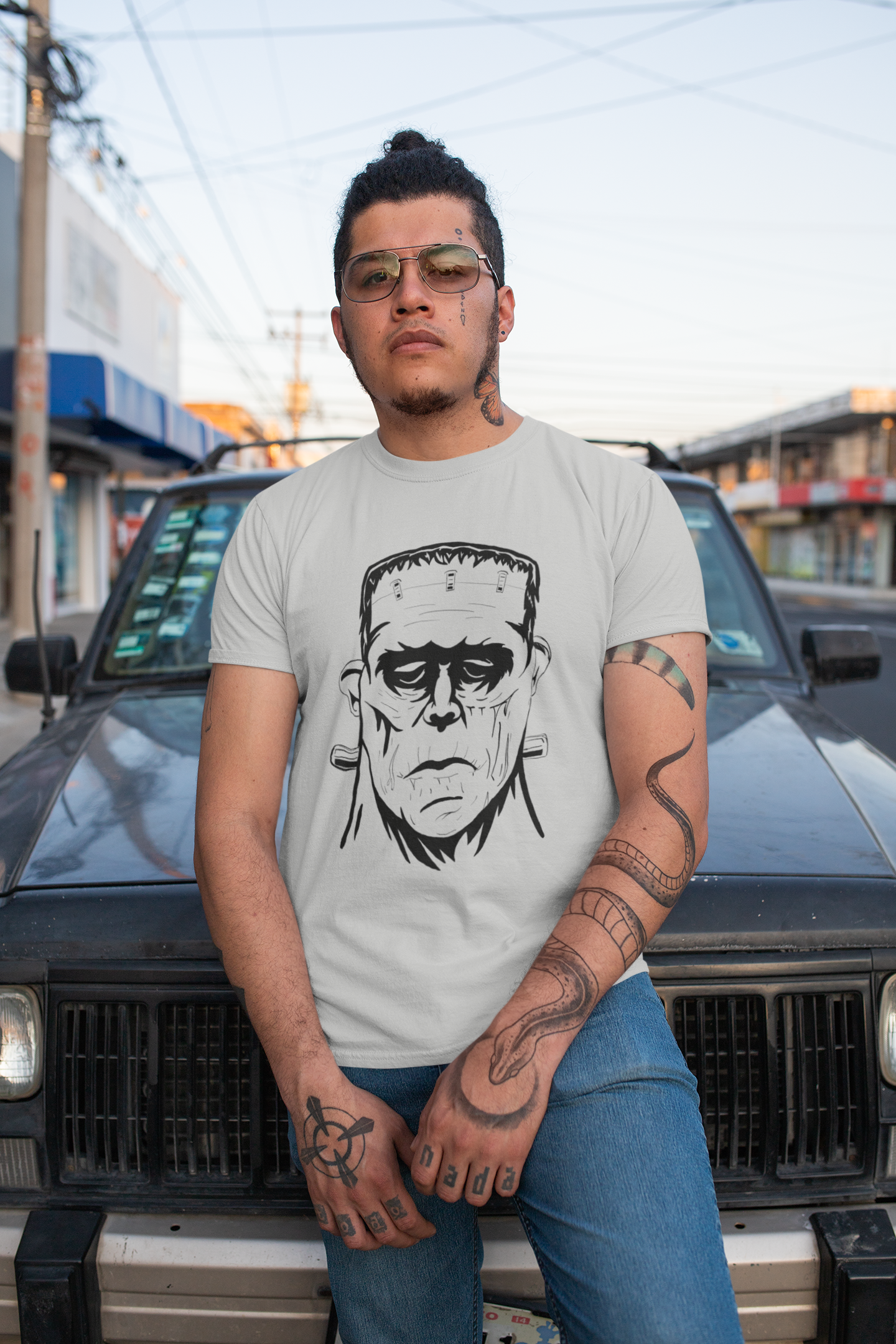 Tattooed man wearing athletic heather gray Frank's Monster t-shirt posing in front of a car