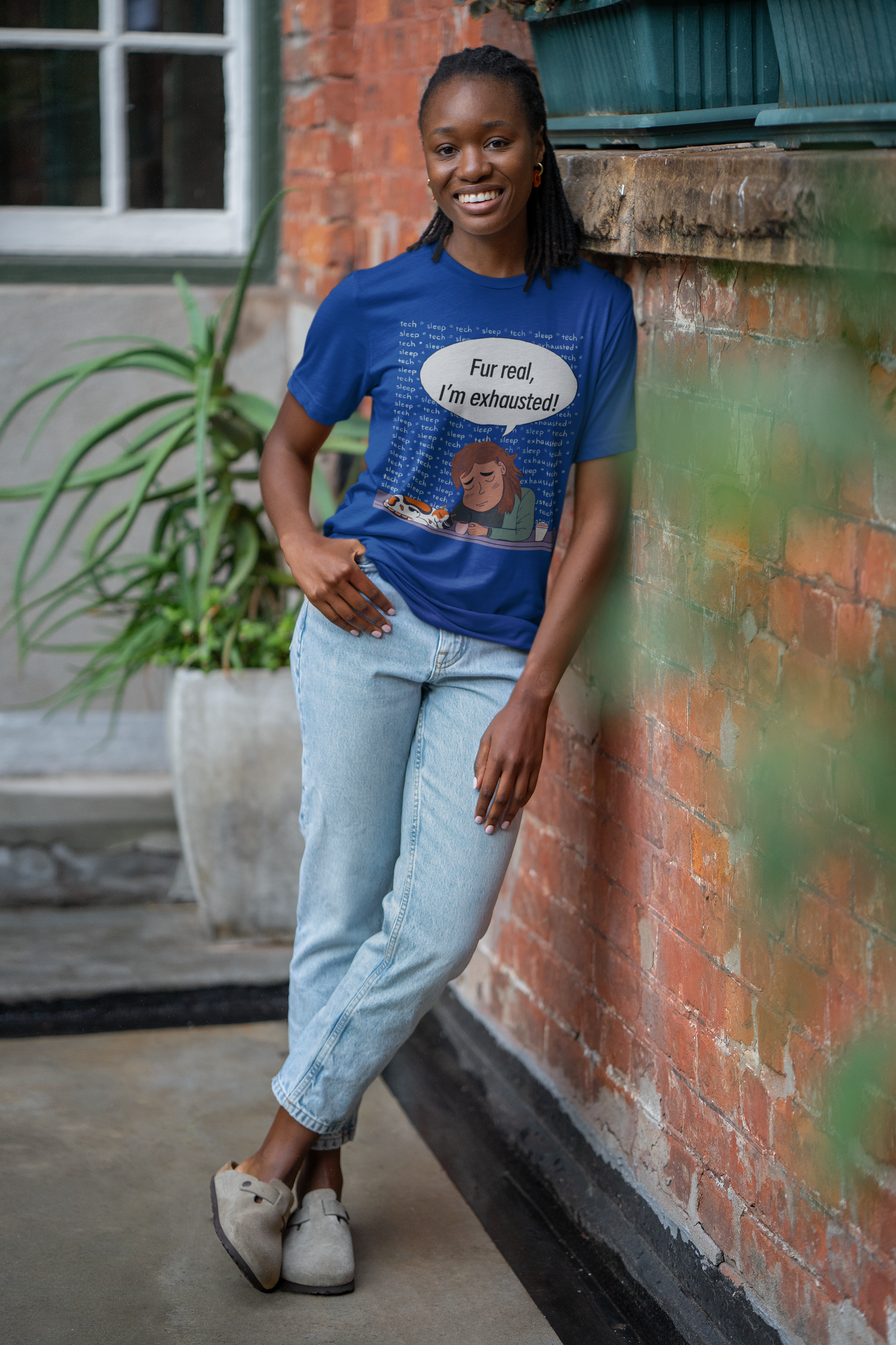 Cheerful woman posing against brick wall in true royal Bella Canvas t-shirt with "Fur Real, I'm Exhausted" colorful vet tech humor design. Relatable sarcastic message for burnt-out animal lovers and vet techs.
