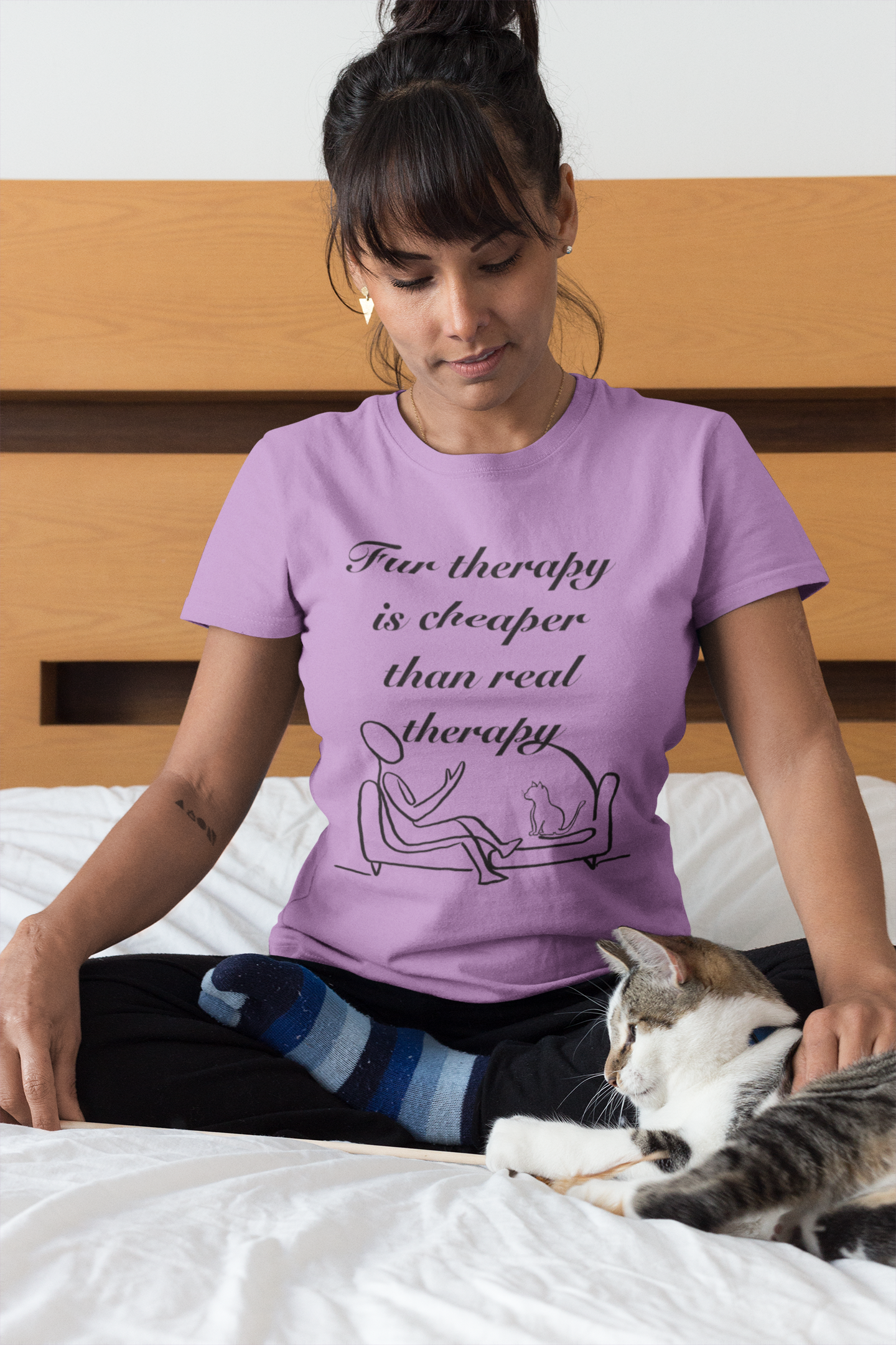 Woman sitting on bed with her cat while wearing heather team purple Fur Therapy is Cheaper Than Real Therapy t-shirt