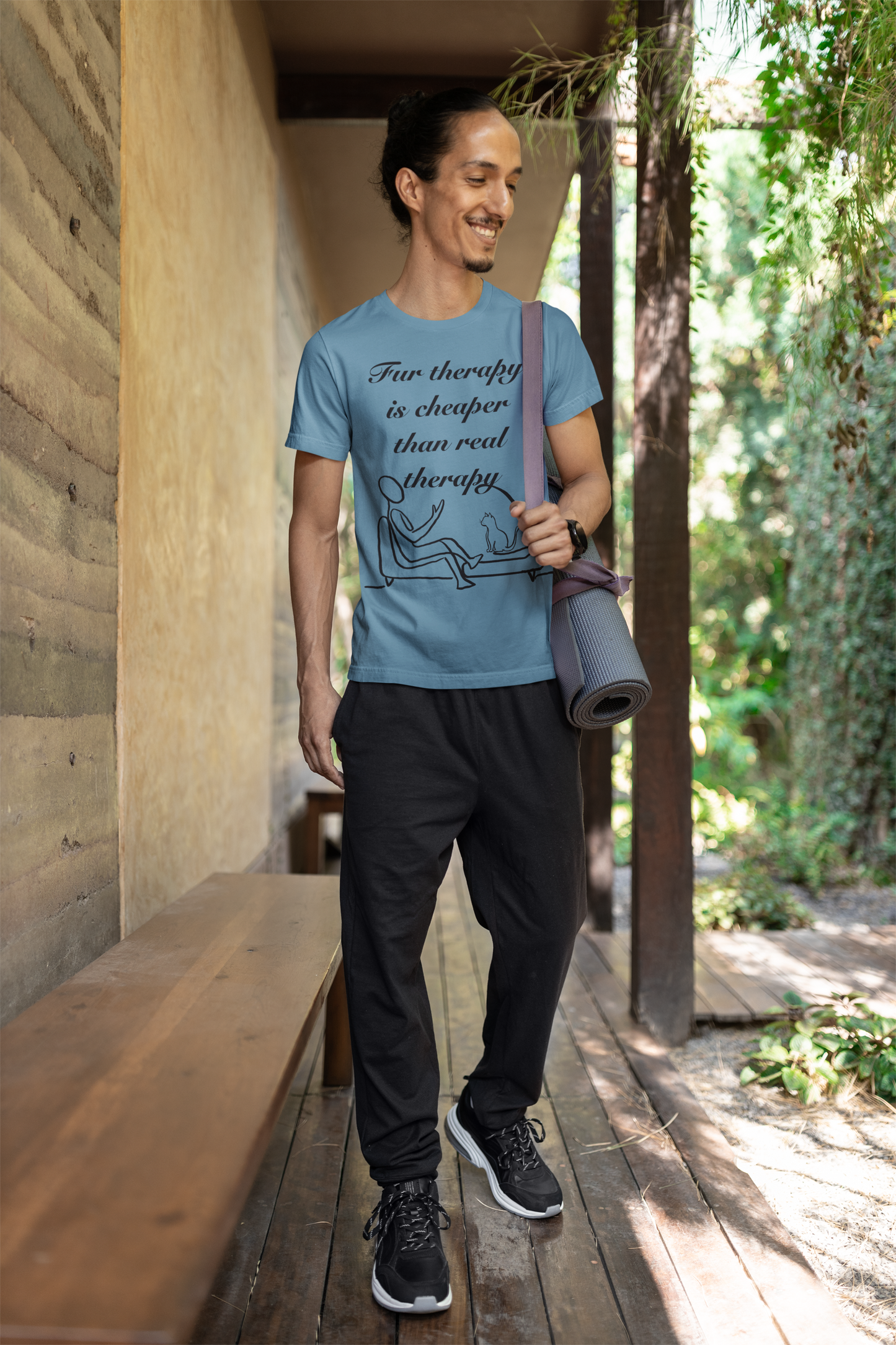 Smiling man with long hair wearing steel blue Fur Therapy is Cheaper Than Real Therapy black ink cat t-shirt while carrying a yoga mat outdoors