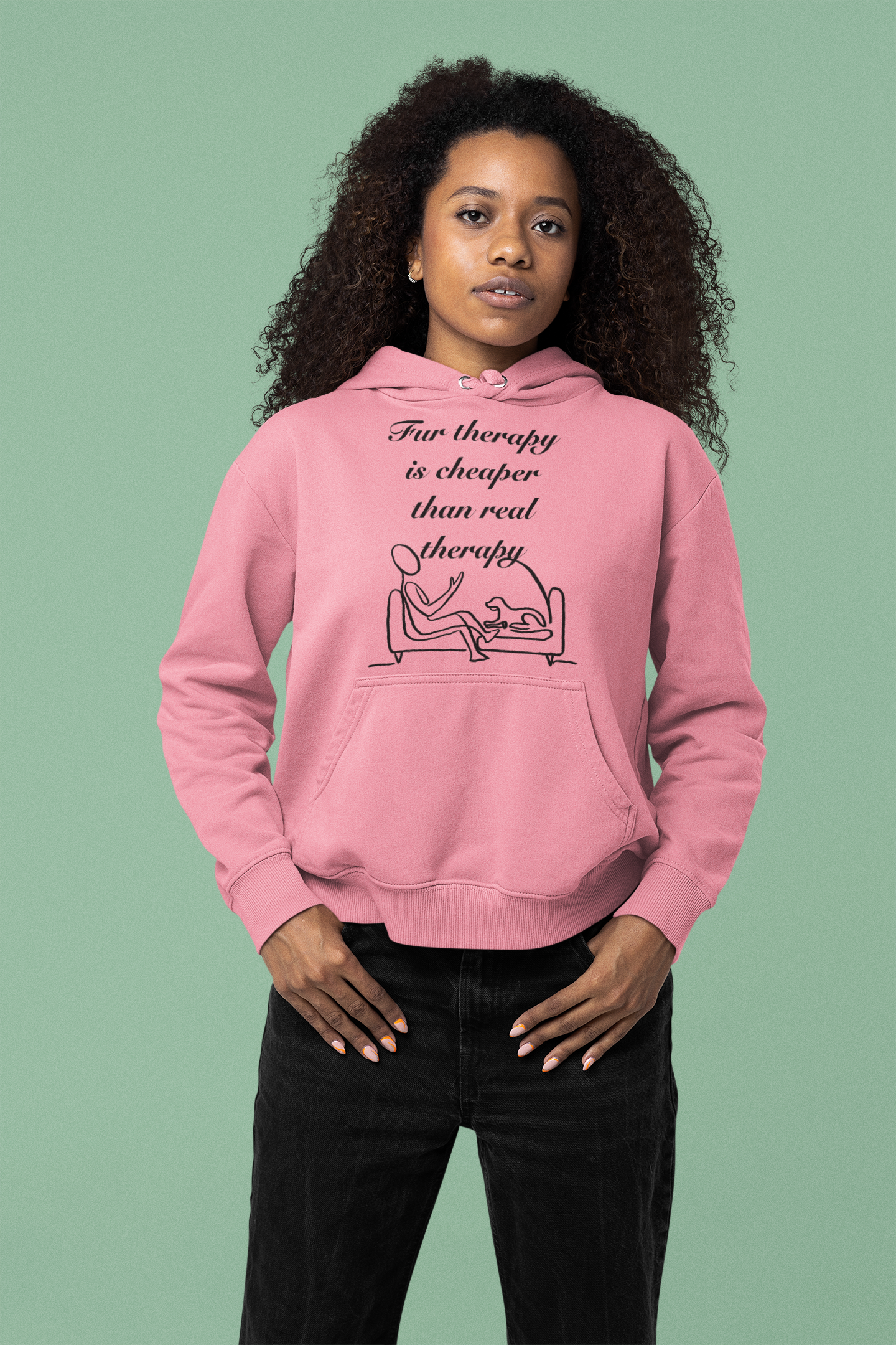 Woman with curly dark hair wearing azalea pink Fur Therapy is Cheaper Than Real Therapy hoodie standing against green background