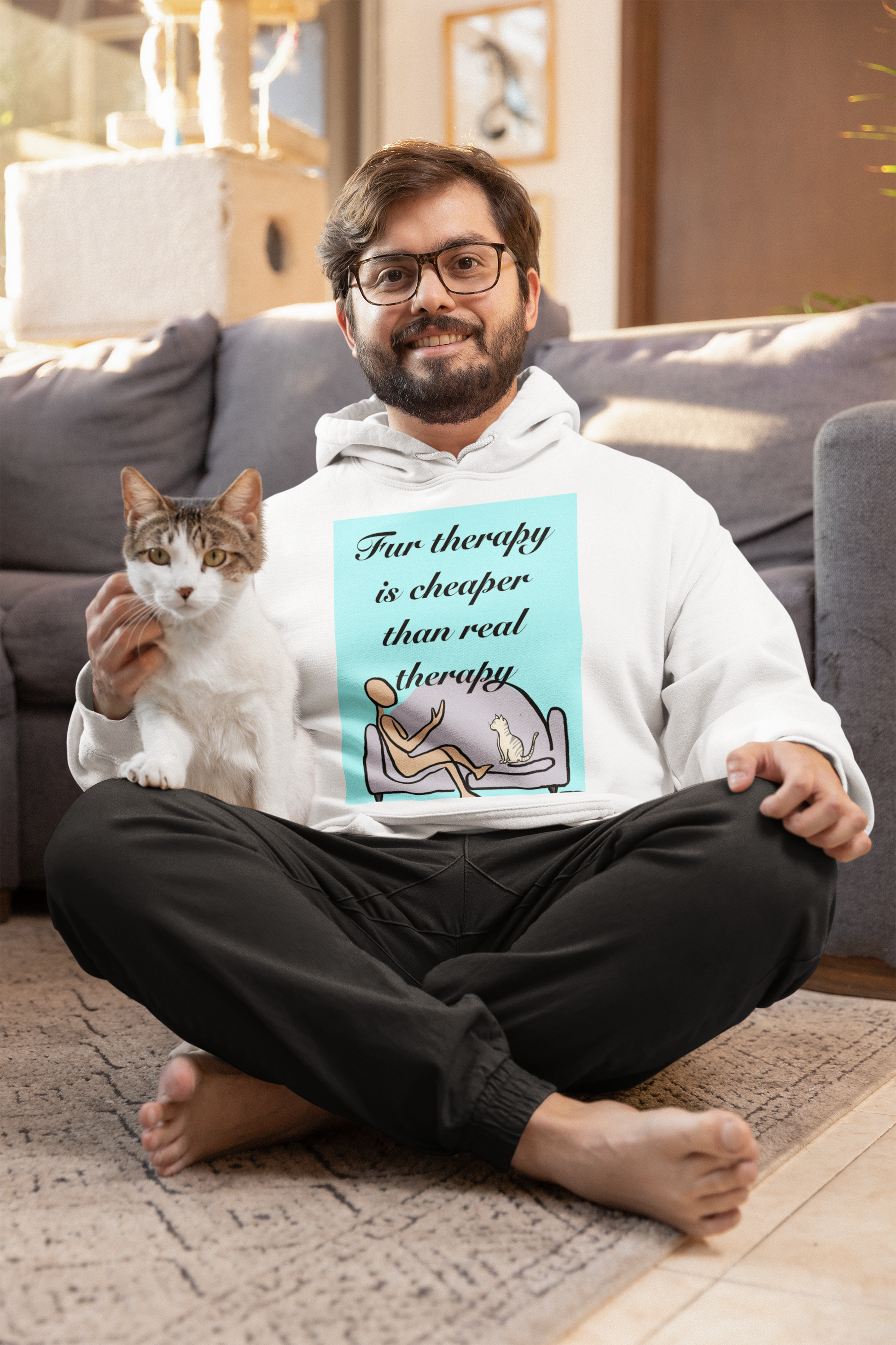 Man sitting on floor with cat on lap wearing white Fur Therapy Is Cheaper Than Real Therapy colored cat hoodie – relatable pet therapy humor by GrungePup Sarcastic Affirmations
