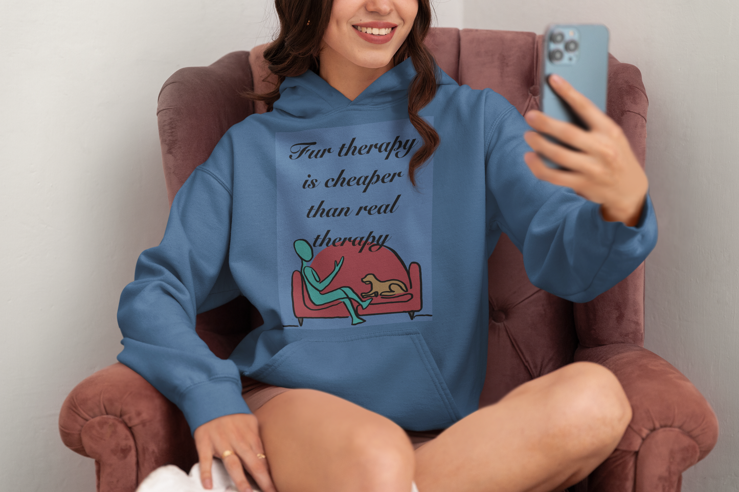 Woman sitting in red chair wearing indigo blue Fur Therapy Is Cheaper Than Real Therapy colored dog hoodie – sarcastic affirmation design by GrungePup Sarcastic Affirmations