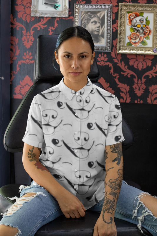 Woman with tattoos sitting in tattoo shop chair wearing GrungePup logo all-over print button down shirt
