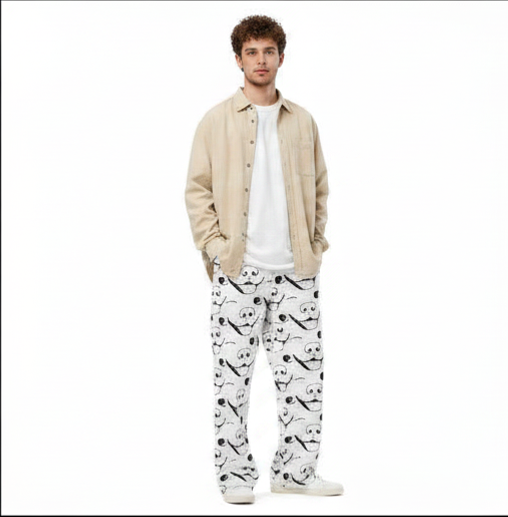 Man with curly hair standing wearing GrungePup logo all-over print wide-leg pants with white t-shirt