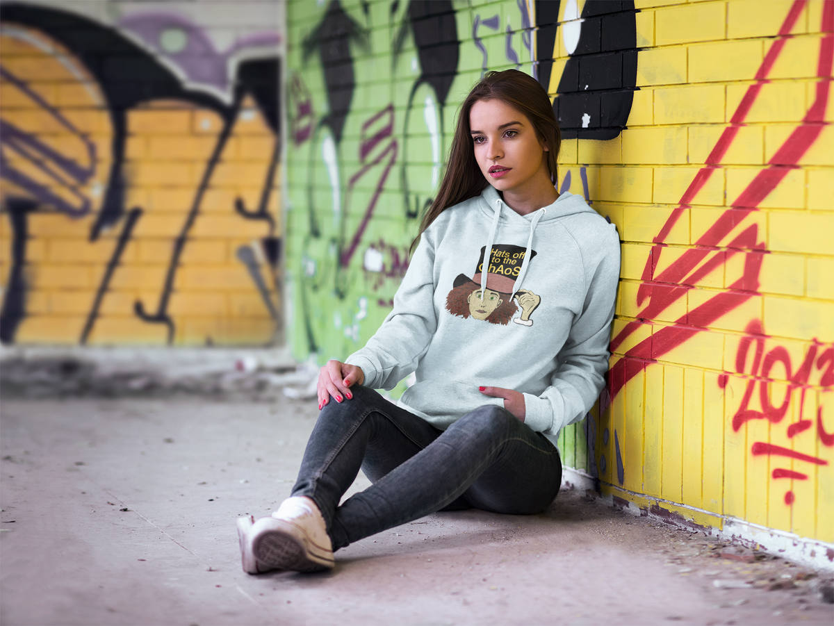 Woman sitting against a yellow graffiti wall in a sky blue Hats Off to the Chaos Mad Hatter hoodie. That Girl, Alice by GrungePup Gallery.