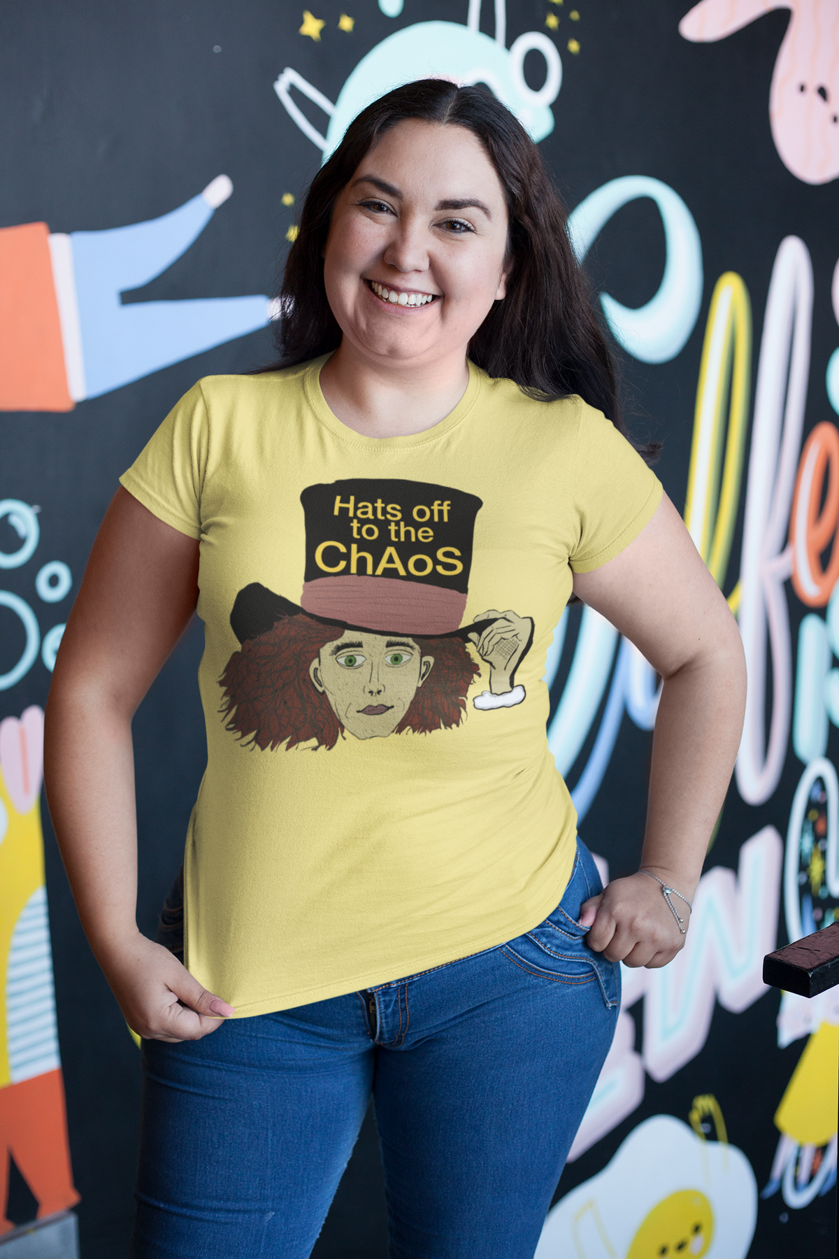 Smiling curvy woman in a cornsilk Hats Off to the Chaos Mad Hatter t-shirt and jeans. That Girl, Alice by GrungePup Gallery.