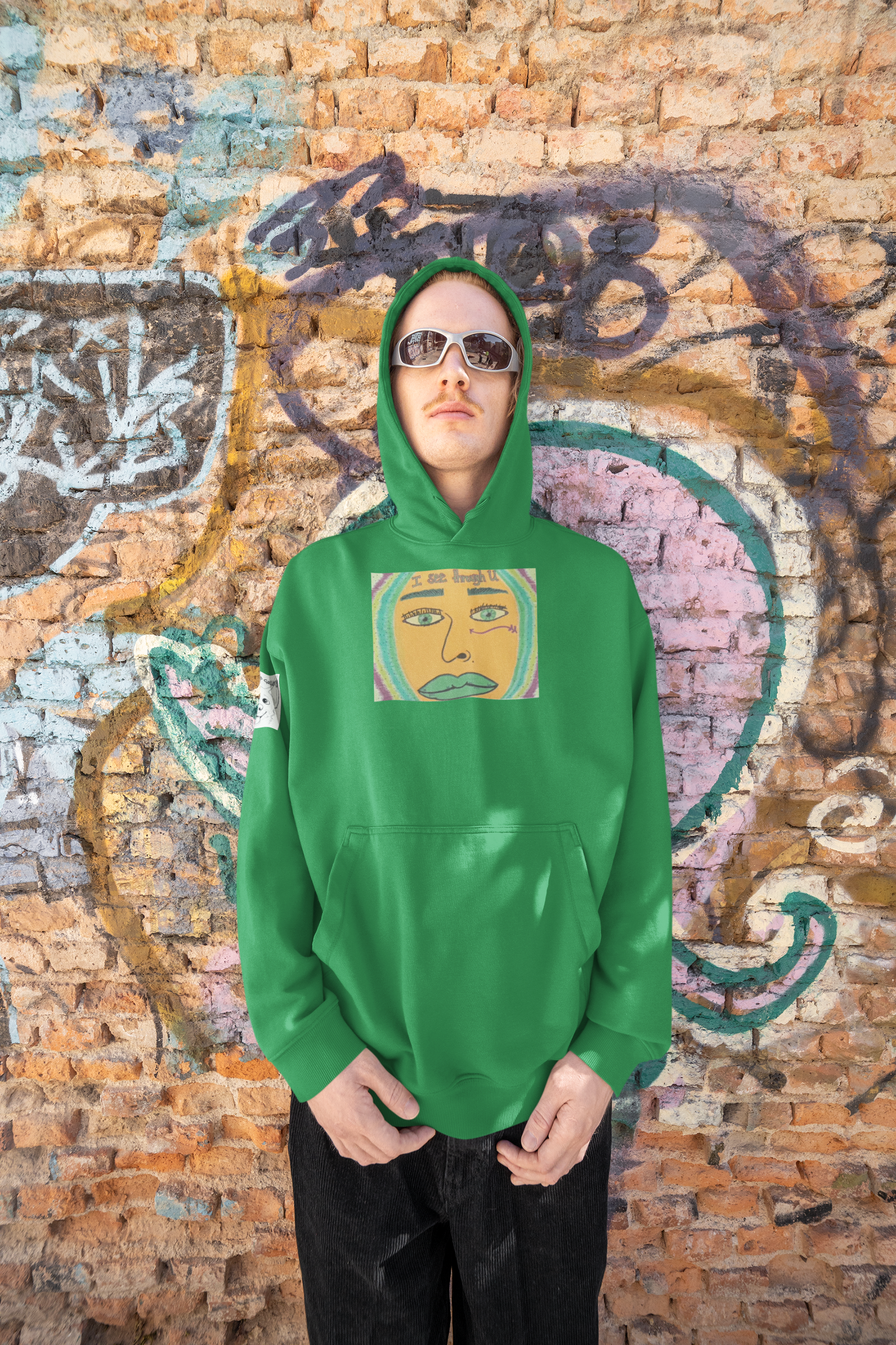 Man wearing irish green I See Through U hoodie standing against colorful graffiti wall