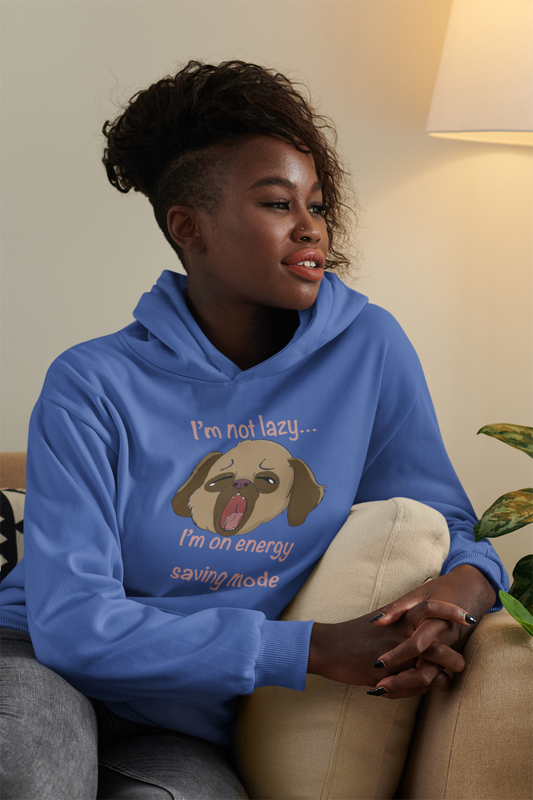 Woman with curly hair sitting on a couch wearing indigo blue I'm Not Lazy... I'm On Energy Saving Mode hoodie with sleepy pup design
