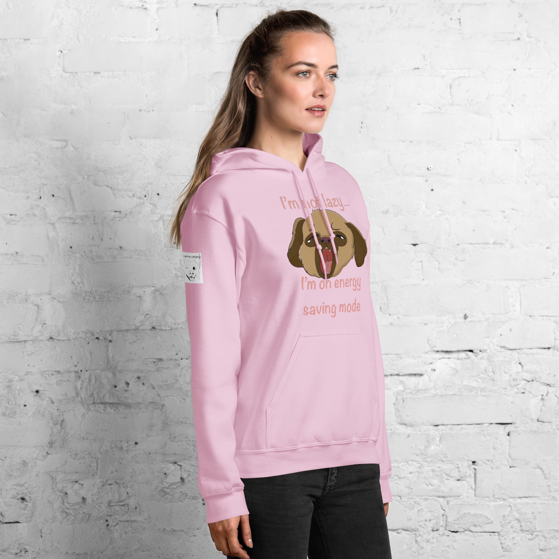 Woman wearing light pink I'm Not Lazy... I'm On Energy Saving Mode hoodie posing in front of white wall