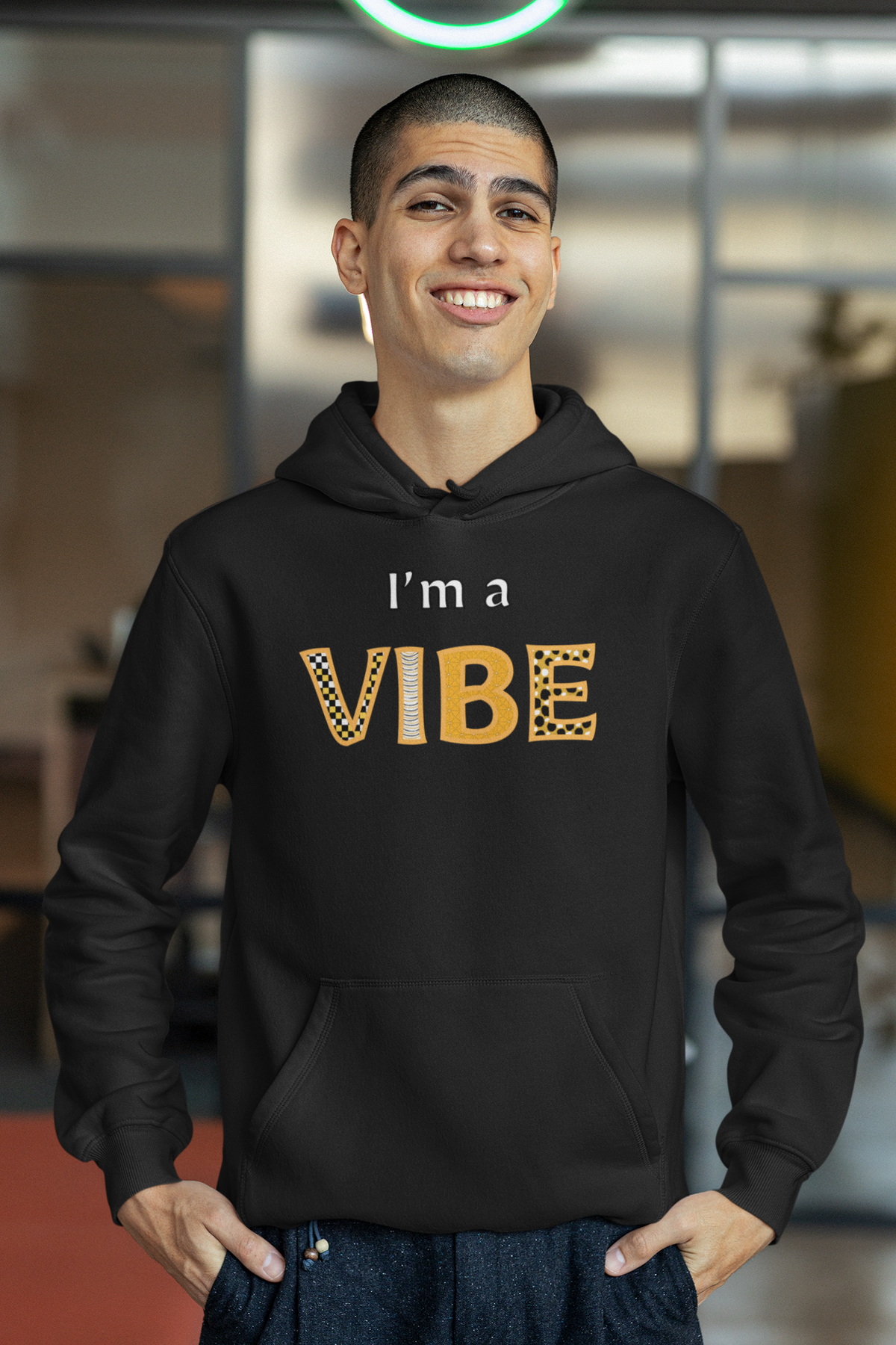 Smiling man with his hands in his pockets wears the black I'm a Vibe hoodie.