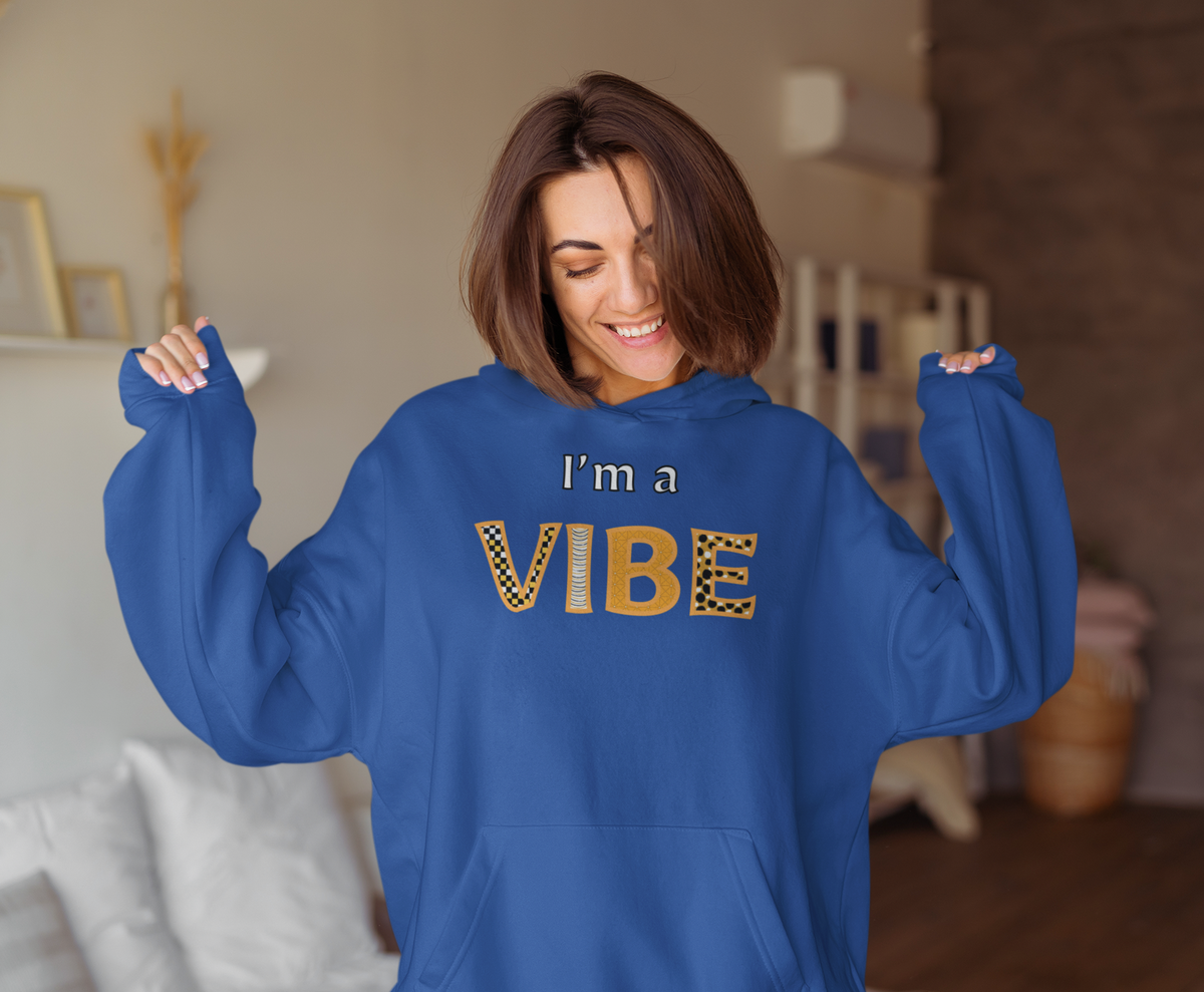 Smiling woman in the royal blue I'm a Vibe hoodie tugs the sleeves down over her hands.