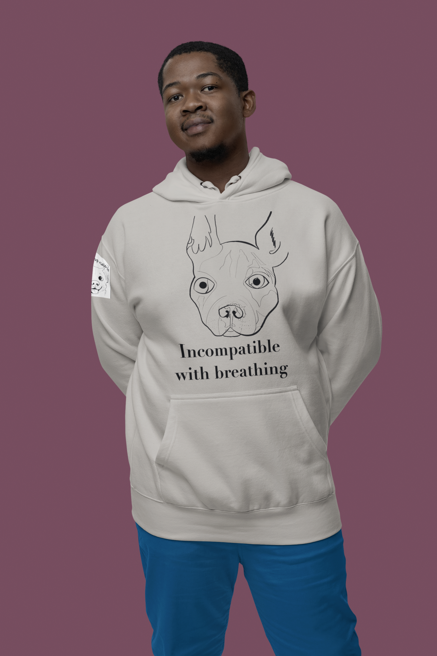 Man smiling and posing against pink background wearing carbon grey Incompatible with Breathing black ink hoodie with French Bulldog design