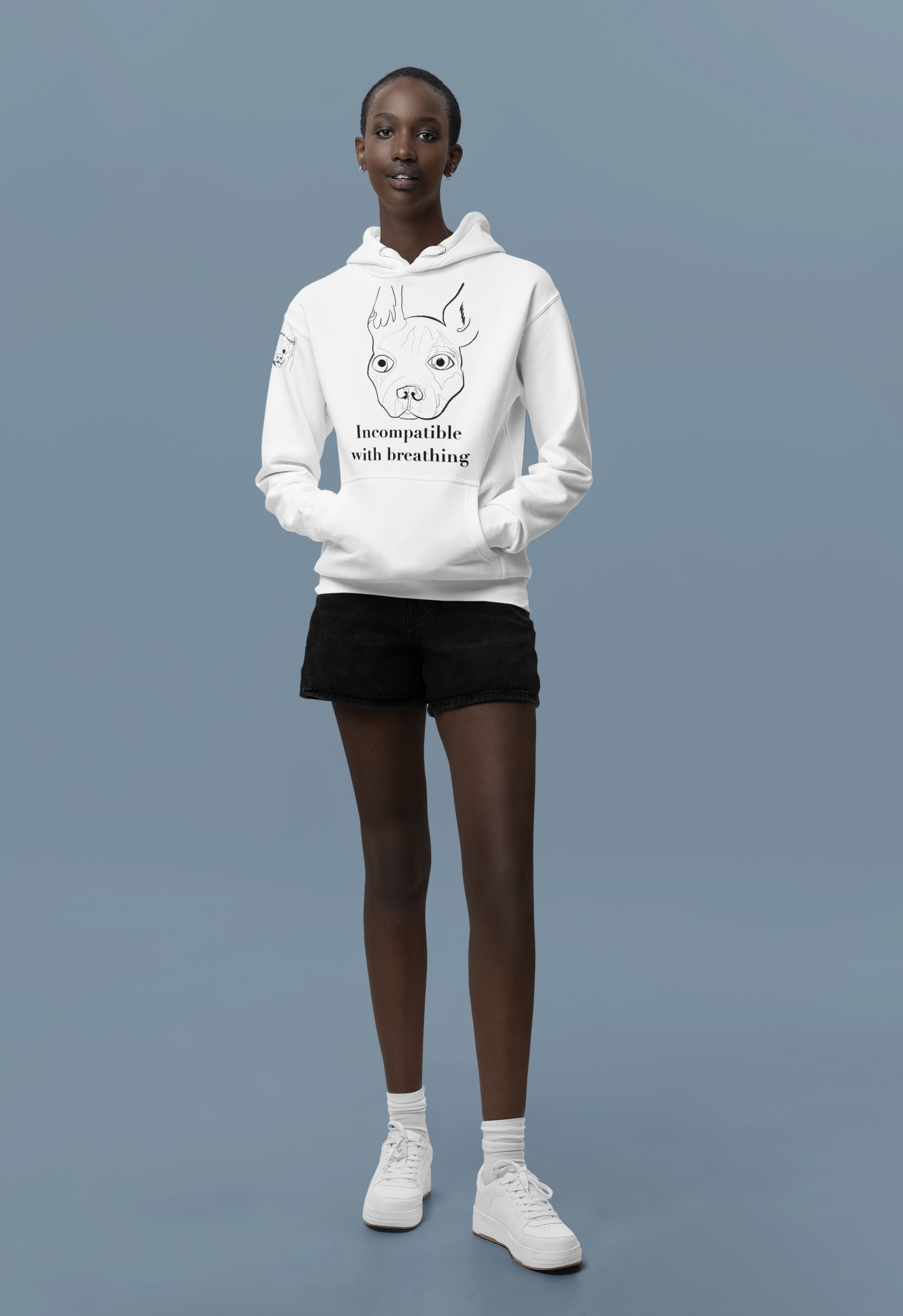 Tall woman standing in blue studio wearing white Incompatible with Breathing black ink hoodie featuring French Bulldog line art