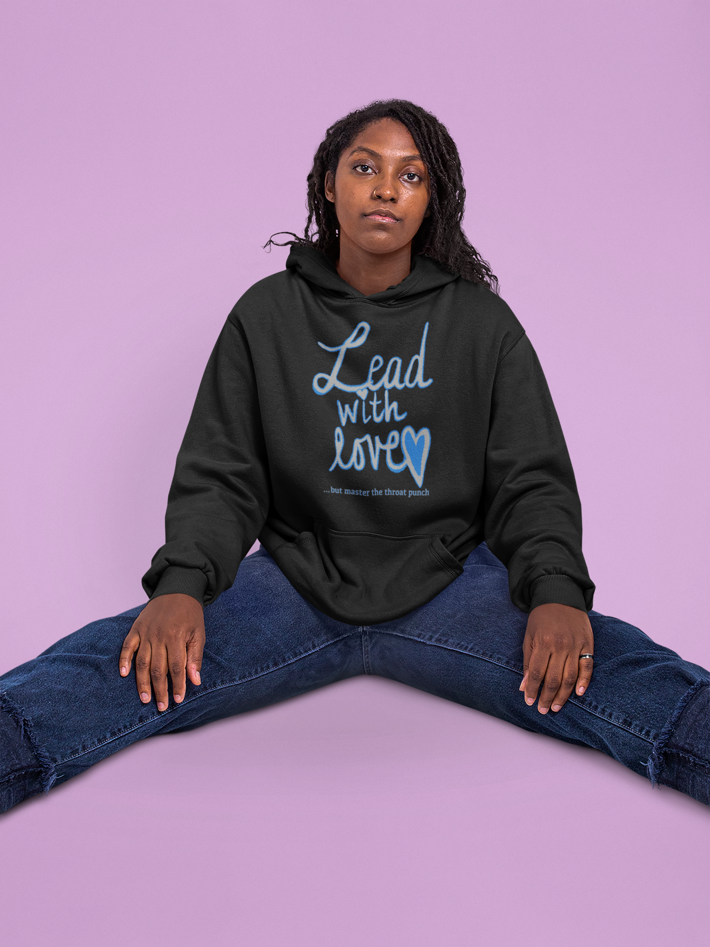 Woman with braids wearing black Gildan 18500 hoodie with "Lead with Love… but master the throat punch" sarcastic design. Bold boundary-setting message for strong yet kind personalities.