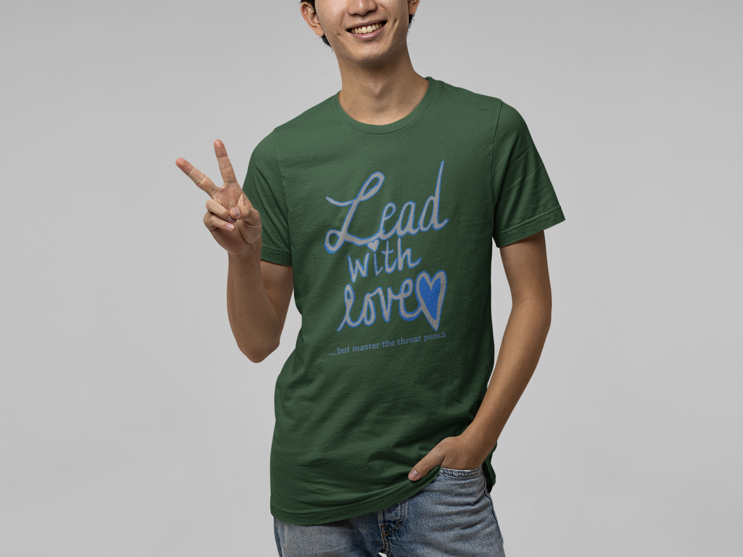 Man standing in forest wearing forest green Bella Canvas t-shirt with "Lead with Love… but master the throat punch" sarcastic self-care design. Bold empowering message for those who lead with kindness but set strong boundaries.