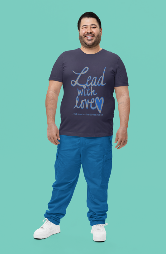 Bearded man smiling in heather midnight navy Bella Canvas t-shirt featuring "Lead with Love… but master the throat punch" sarcastic self-care design. Strong yet heartfelt message for men who protect their peace.