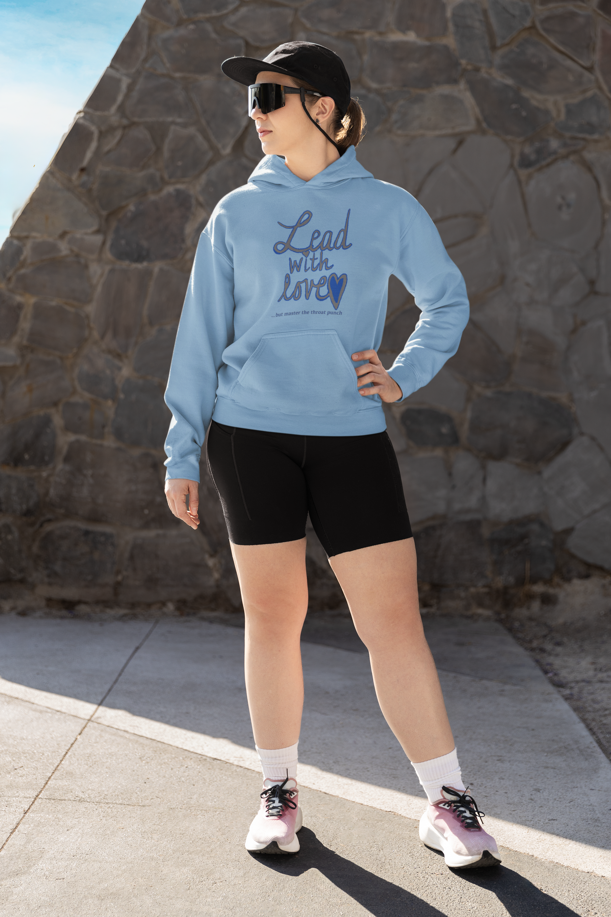 Woman in light blue Gildan 18500 hoodie outdoors showcasing "Lead with Love… but master the throat punch" sarcastic self-care graphic. Perfect for those who lead with kindness but hold firm boundaries.