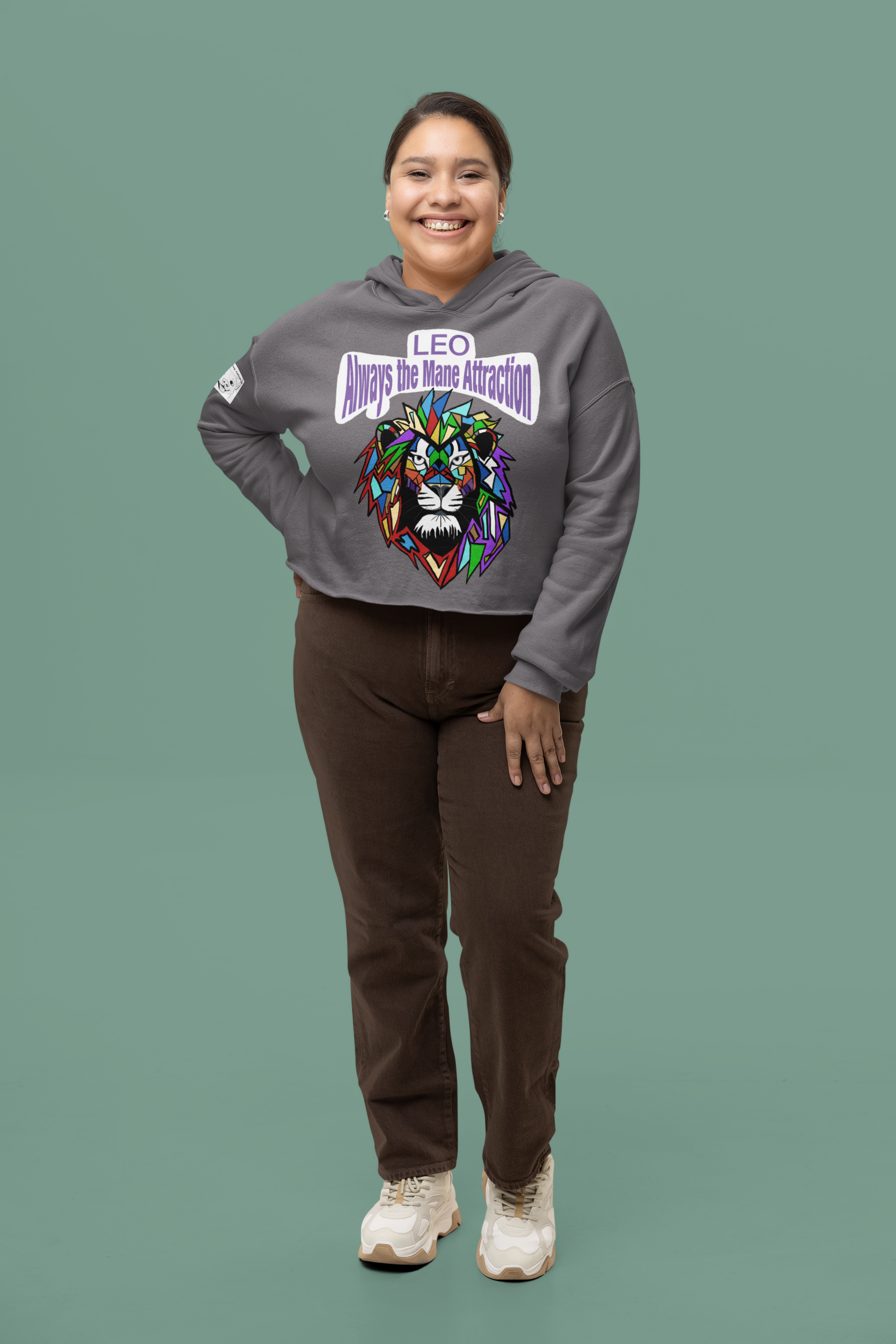 Smiling woman standing in a Storm gray Bella + Canvas 7502 cropped hoodie featuring the Leo Always the Mane Attraction colorful mosaic lion design