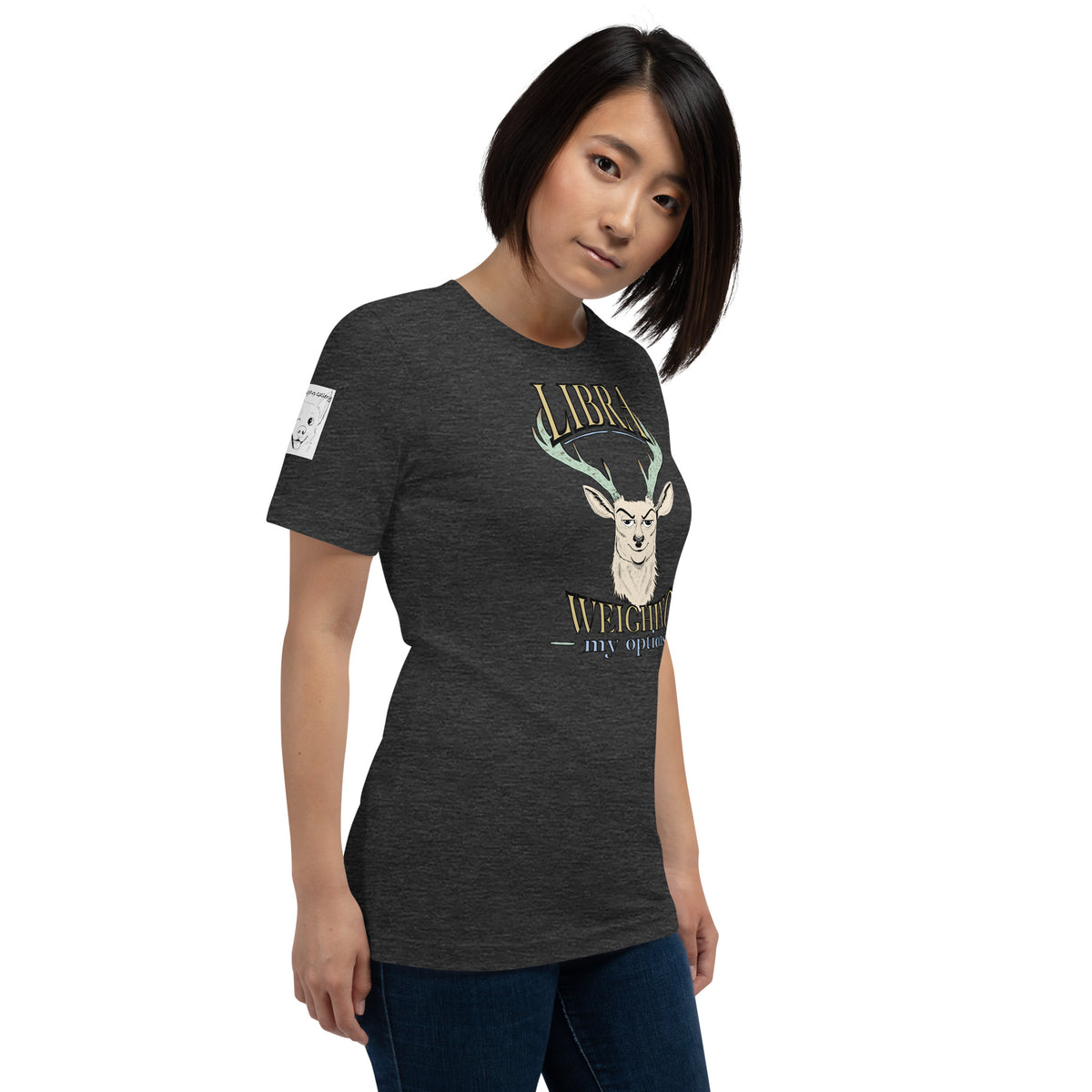 Woman with a short bob wearing a dark grey heather Libra Weighing My Options tee, cream stag, mint antlers, and gold lettering.