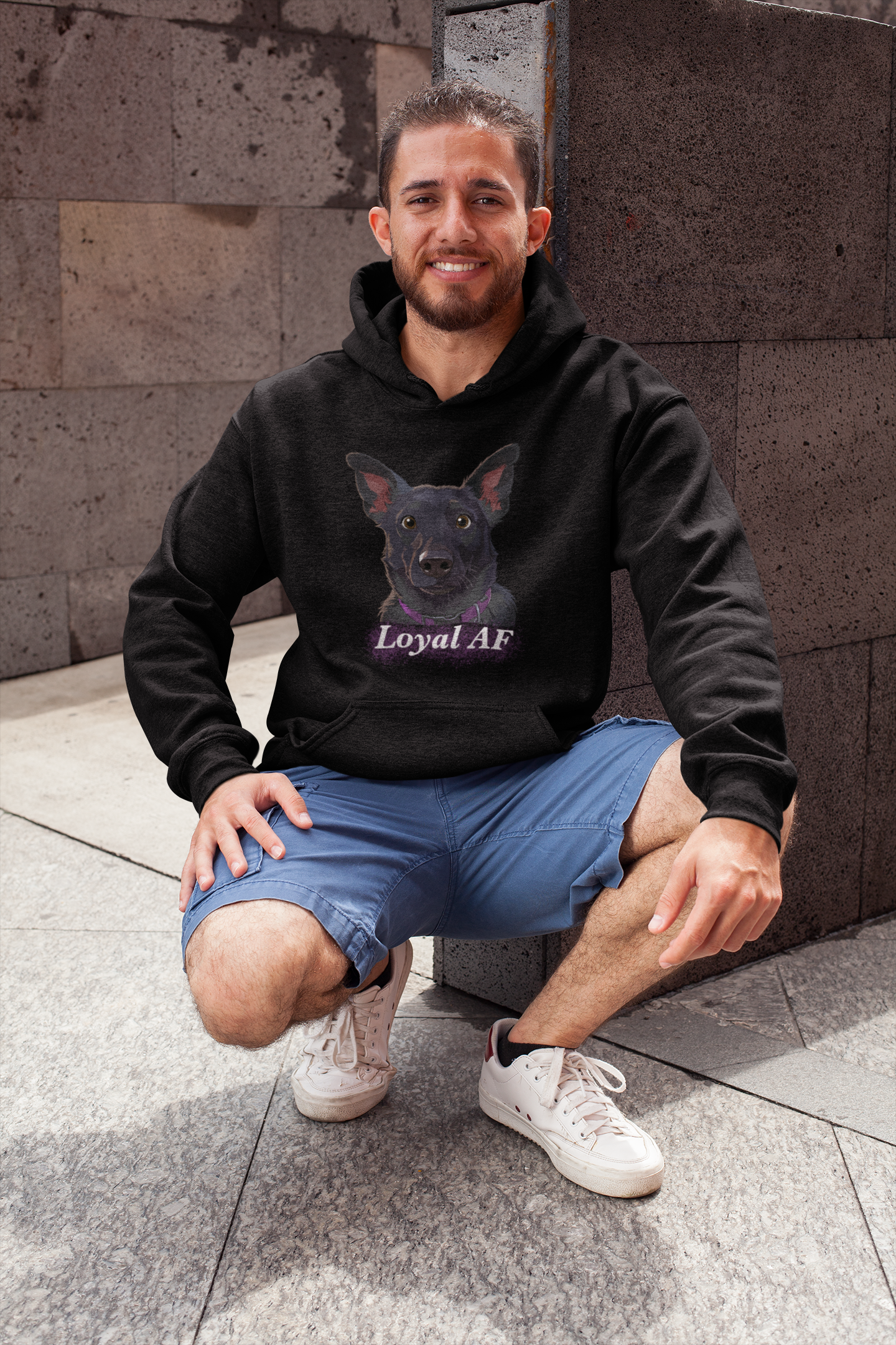 Man smiling while crouching outdoors wearing a black Gildan hoodie with Mathis Loyal AF portrait