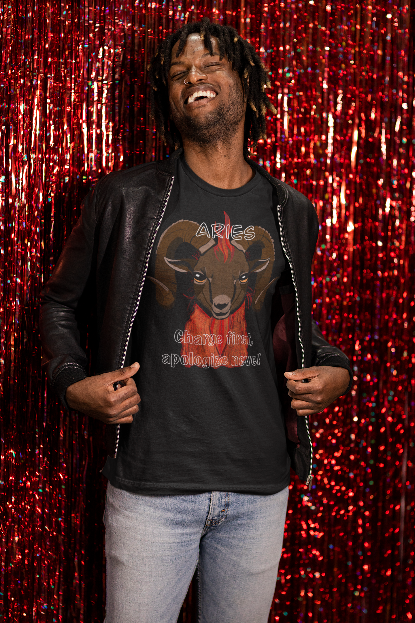 Man laughing in front of red curtain while wearing a black Bella + Canvas t-shirt featuring the Aries ram design