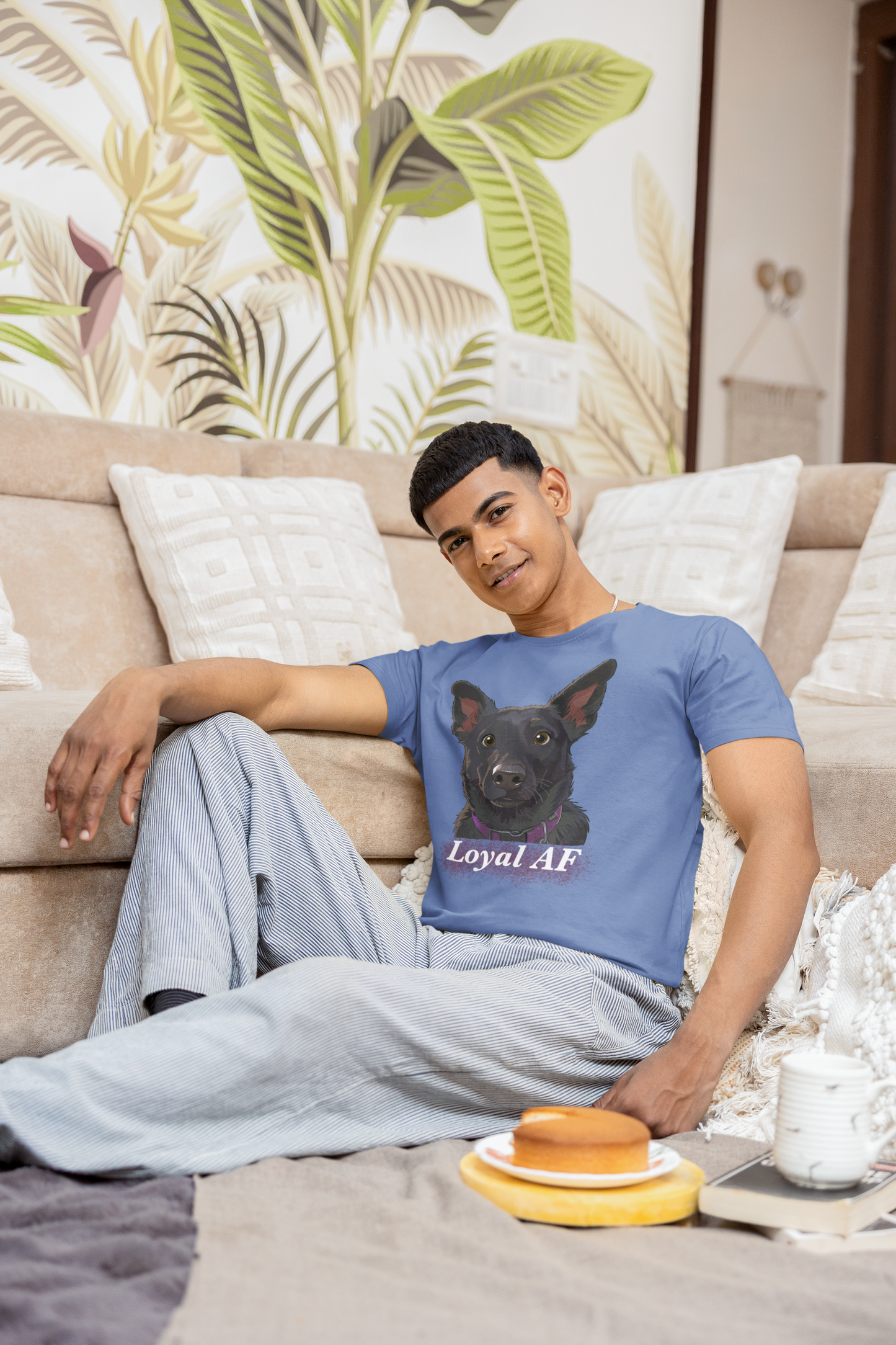 Man relaxing on couch in living room wearing a heather royal blue t-shirt with Mathis Loyal AF portrait