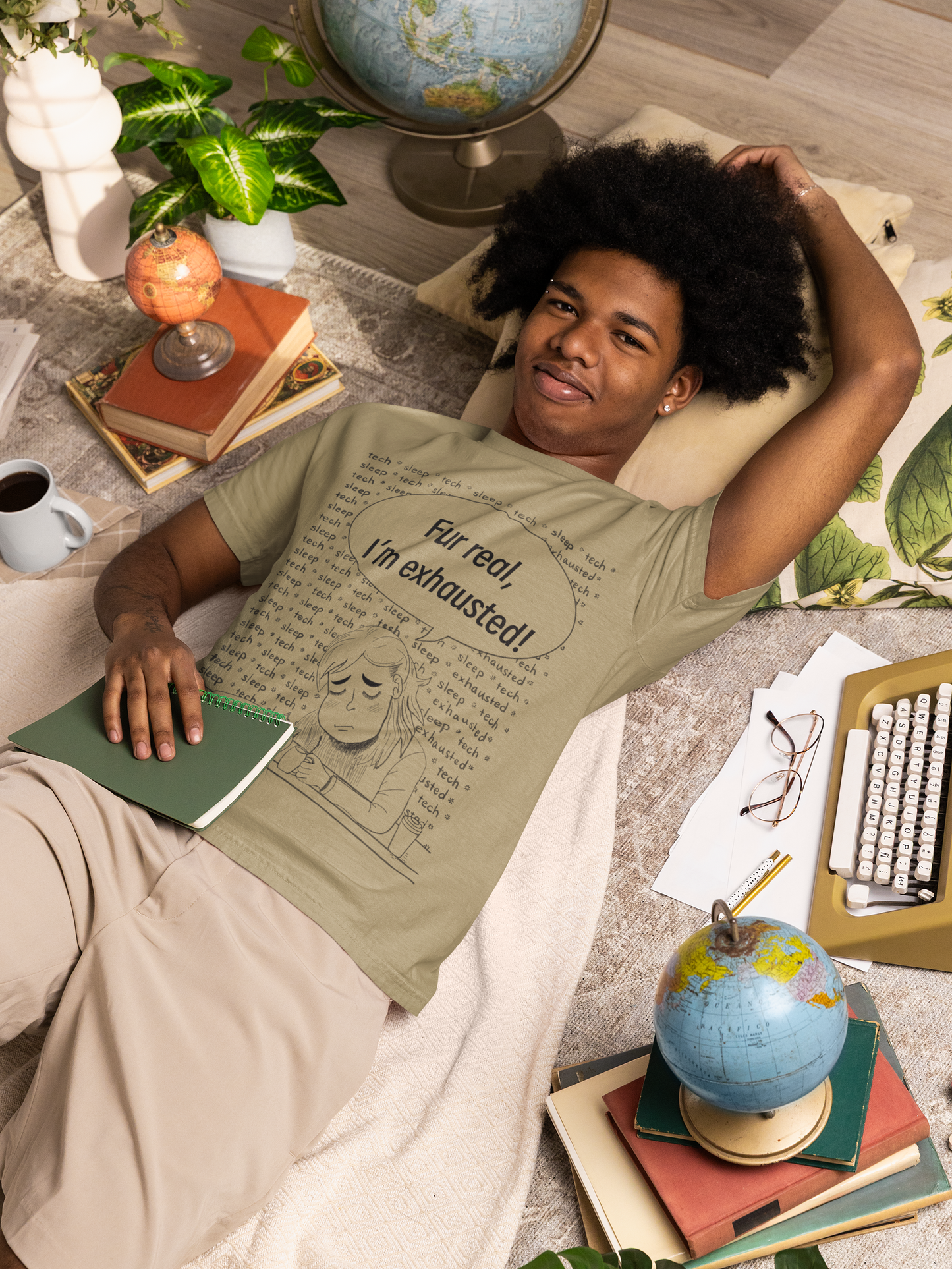 Man with afro lying on the floor surrounded by books wearing a khaki Fur Real, I'm Exhausted t-shirt