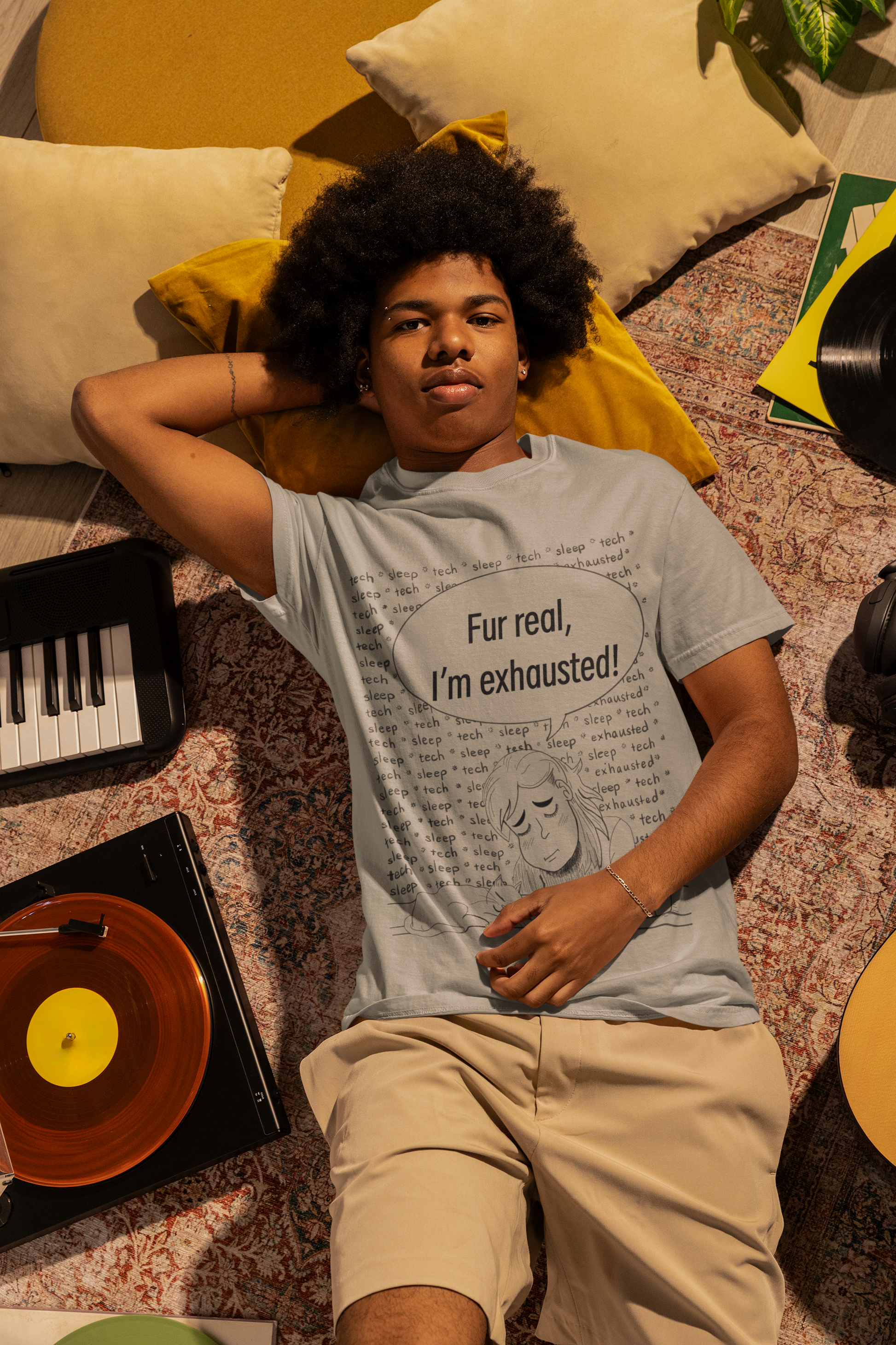 Man with afro lying on the floor surrounded by records and music equipment wearing a granite grey Fur Real, I'm Exhausted t-shirt