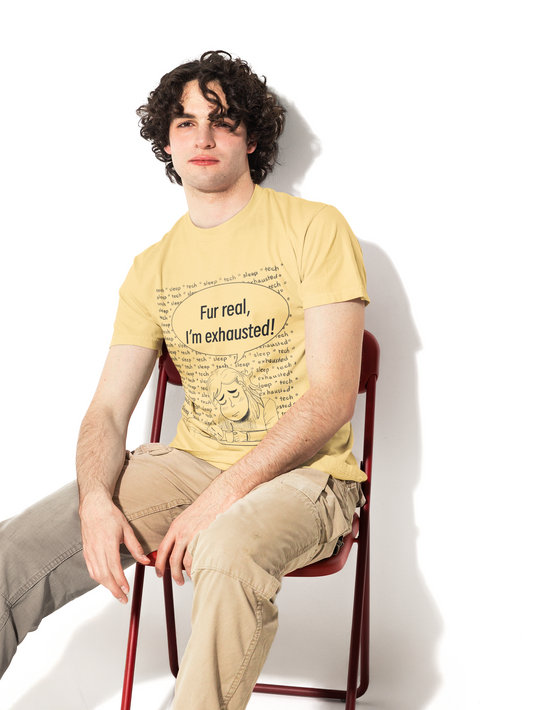 Man with curly dark hair wearing a butter yellow Fur Real, I'm Exhausted t-shirt sitting on a red chair