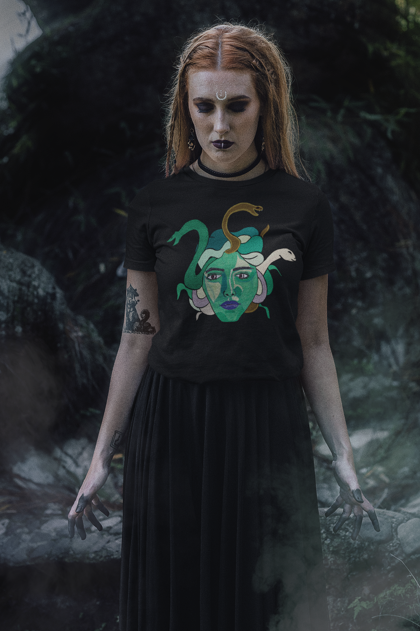 Redheaded woman standing in a misty forest with arms down, wearing a black heather Medusa t-shirt by GrungePup Gallery