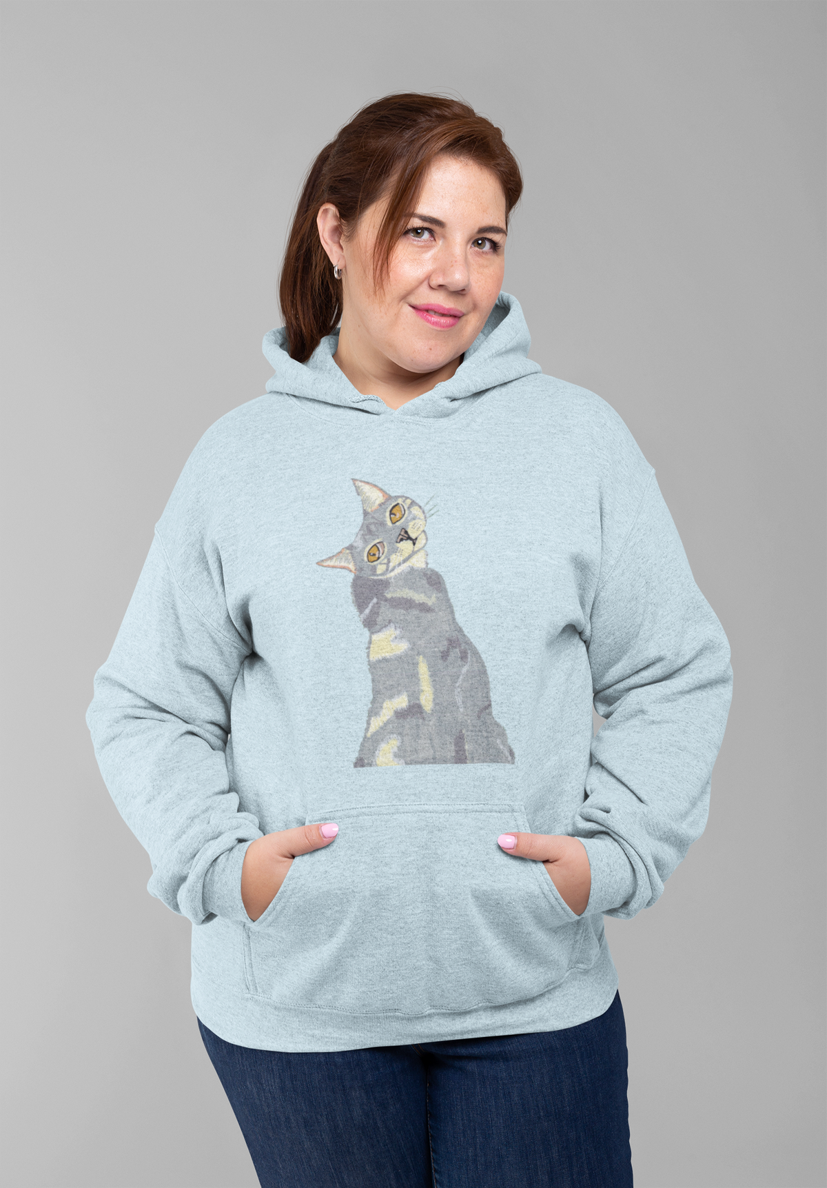Woman with a ponytail standing in a studio, wearing the Mr. Grey Cat Portrait Hoodie in sky blue.