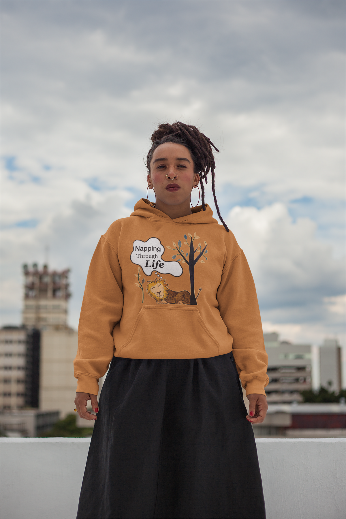 Adobe hoodie featuring the Napping Through Life design. Model with locs on a city rooftop, calm and unbothered energy.