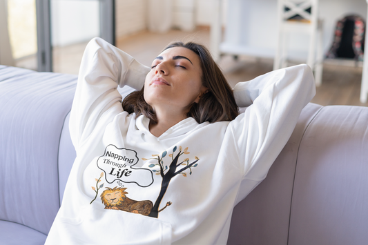 White hoodie, full relax mode on the couch. Hands behind head, eyes closed — the ultimate Napping Through Life energy.